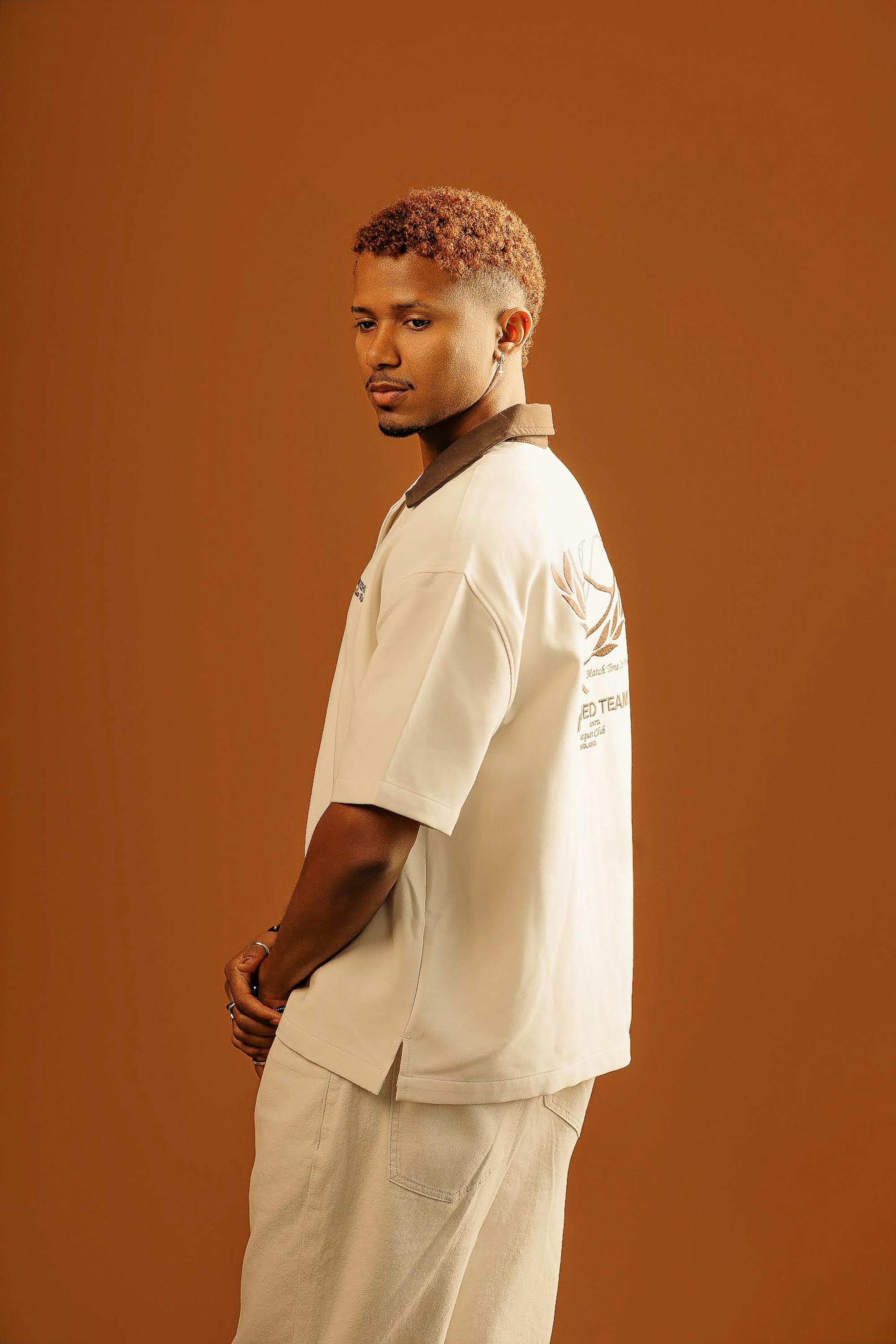 Miễn phí Chân dung một chàng trai trẻ với vẻ mặt ấm áp và trang phục giản dị, trên nền màu nâu. Ảnh lưu trữ