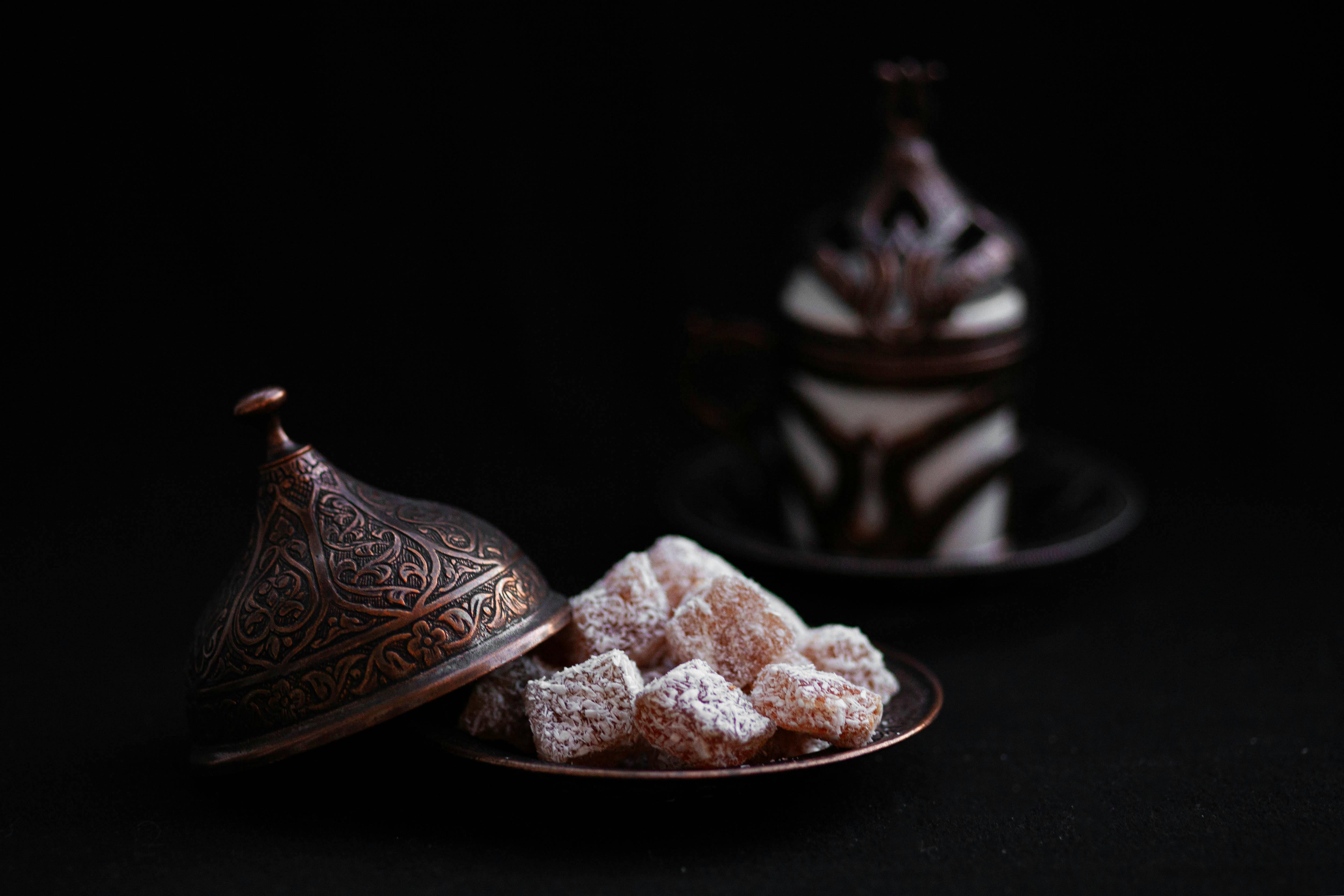 Ilmainen Lähikuva turkkilaisesta herkusta koristeellisessa kuparivadissa, taustalla perinteinen kahvikuppi. Kuvapankkikuva