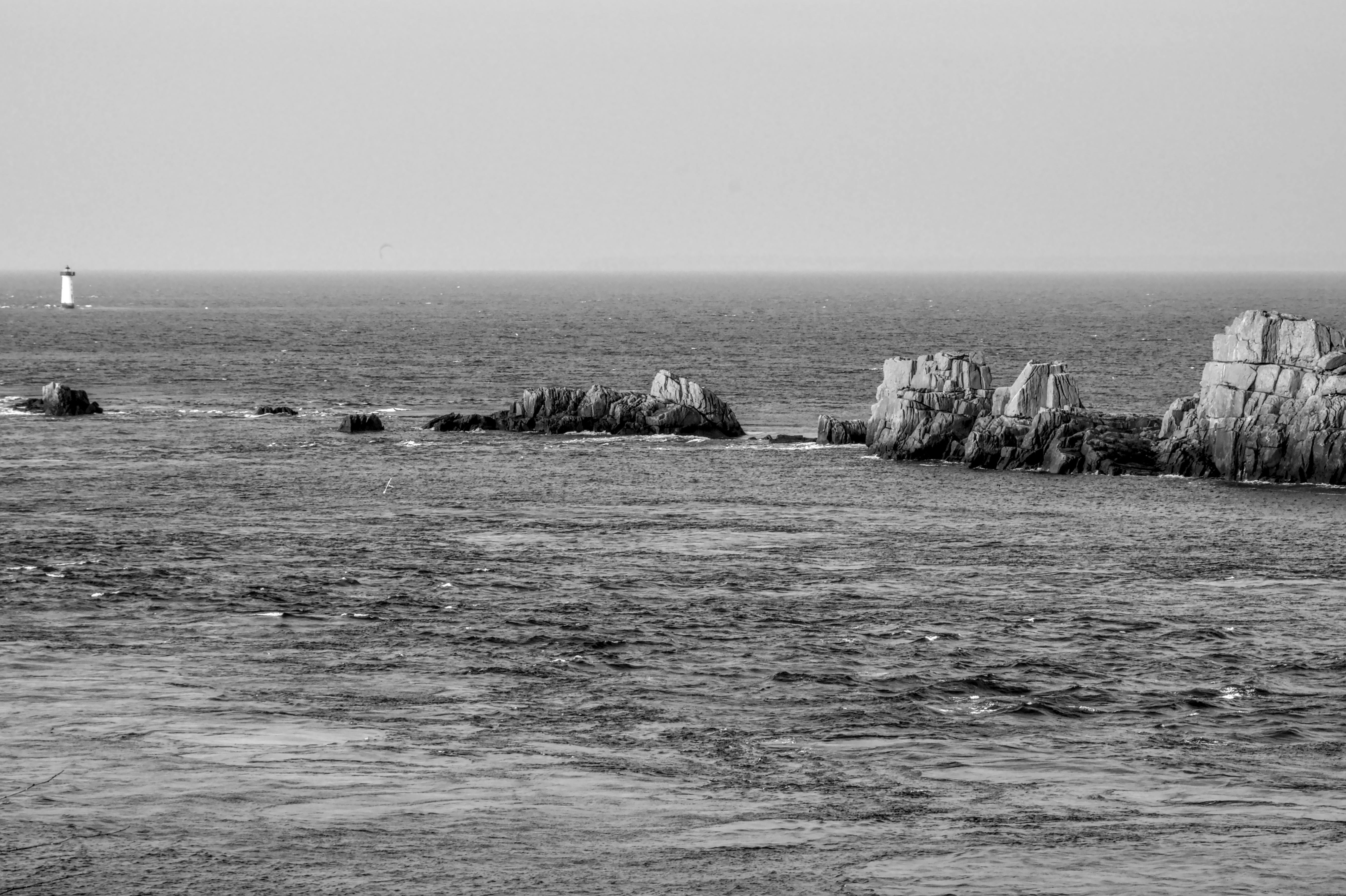 Gratis Imagen monocromática de una costa rocosa y un faro bajo un cielo despejado. Foto de stock