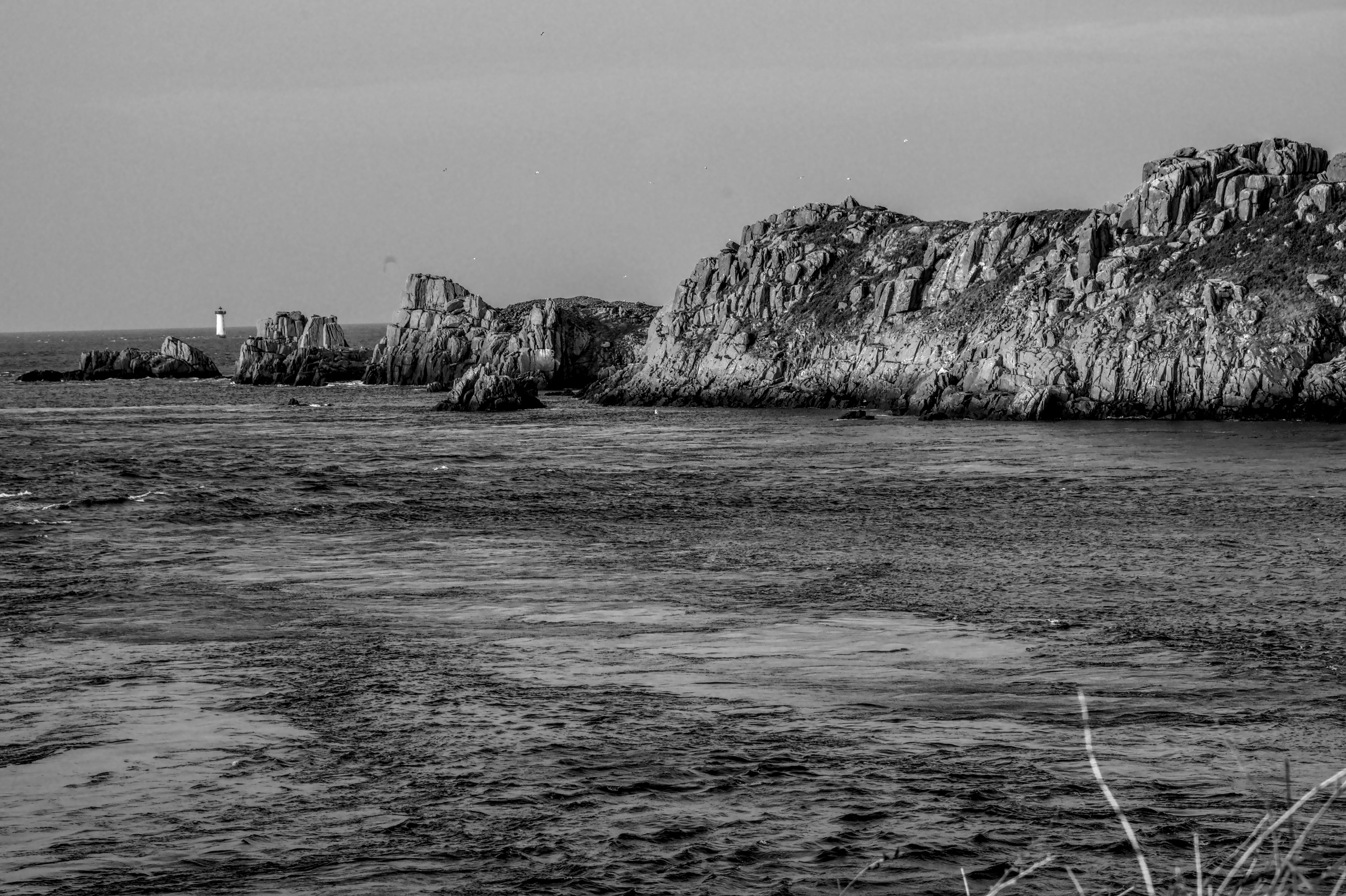Gratis Splendida cattura in bianco e nero della costa rocciosa con un faro in Bretagna, Francia. Foto a disposizione