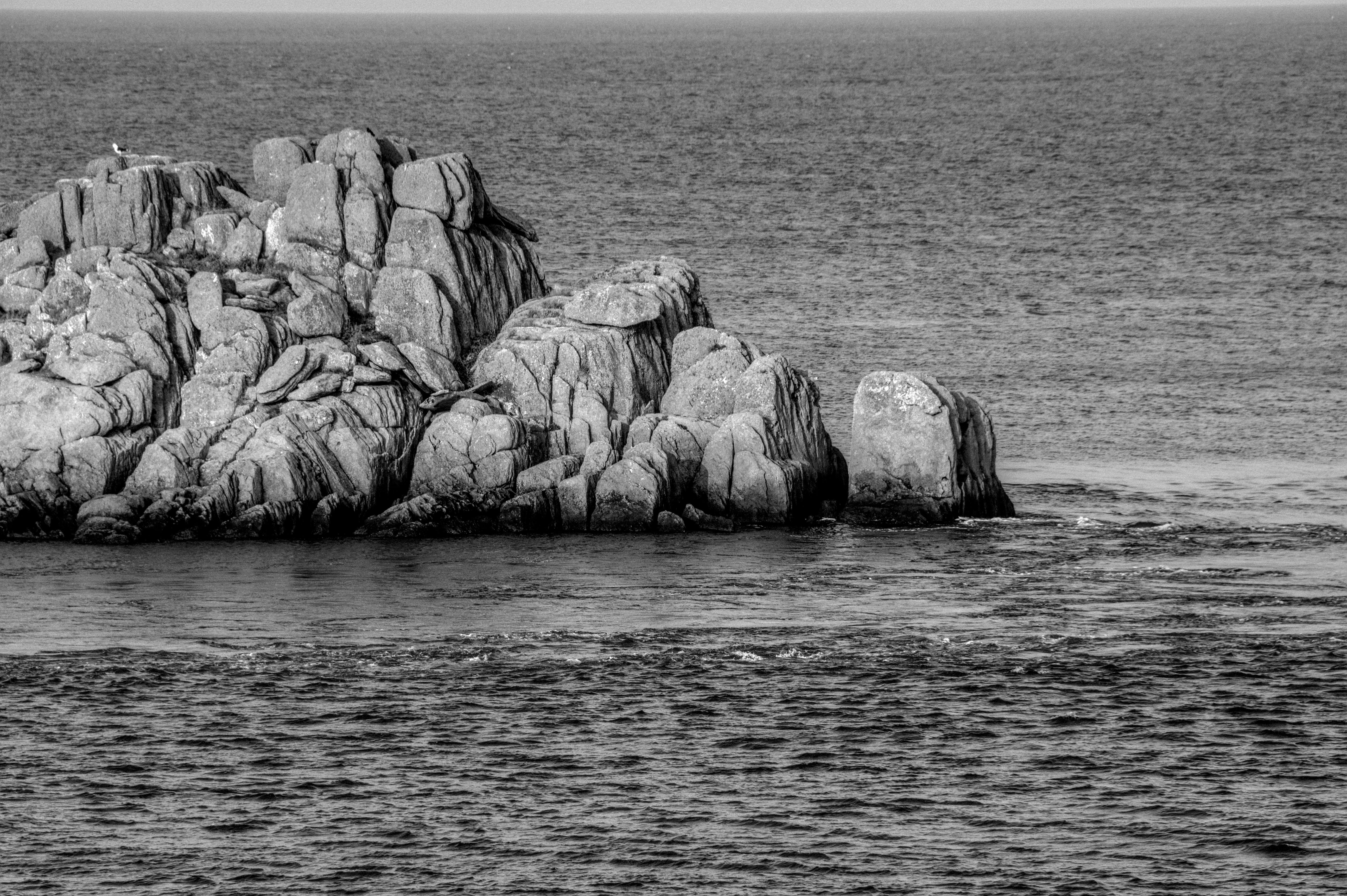 bezplatná Monochromatický pohled na drsné pobřežní skály v Bretani ve Francii, které ukazují přírodní krásy. Základová fotografie