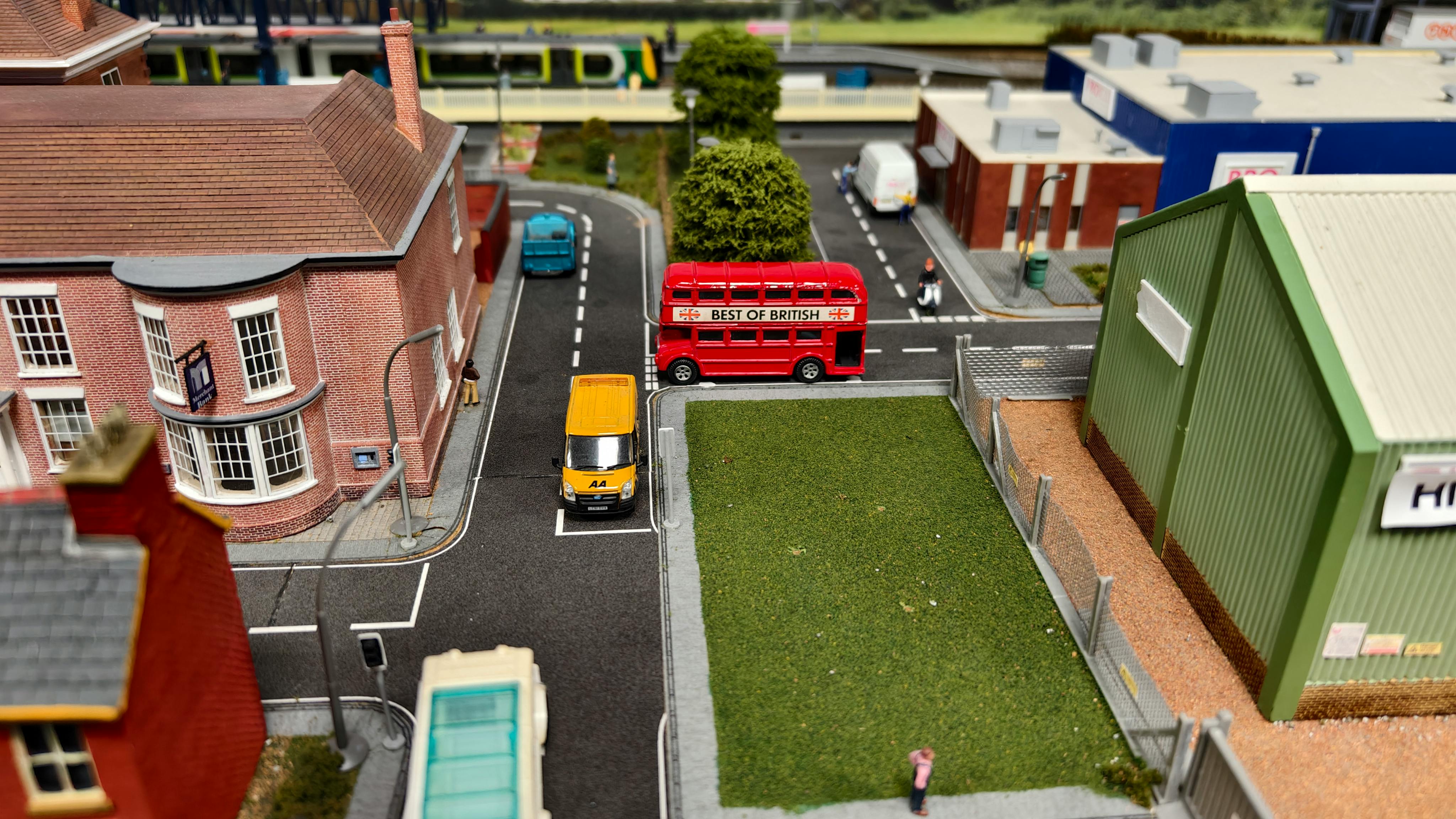 gratis Gedetailleerde modelspoorbaan met een klassieke rode dubbeldekkerbus en omringende miniatuurarchitectuur. Stockfoto