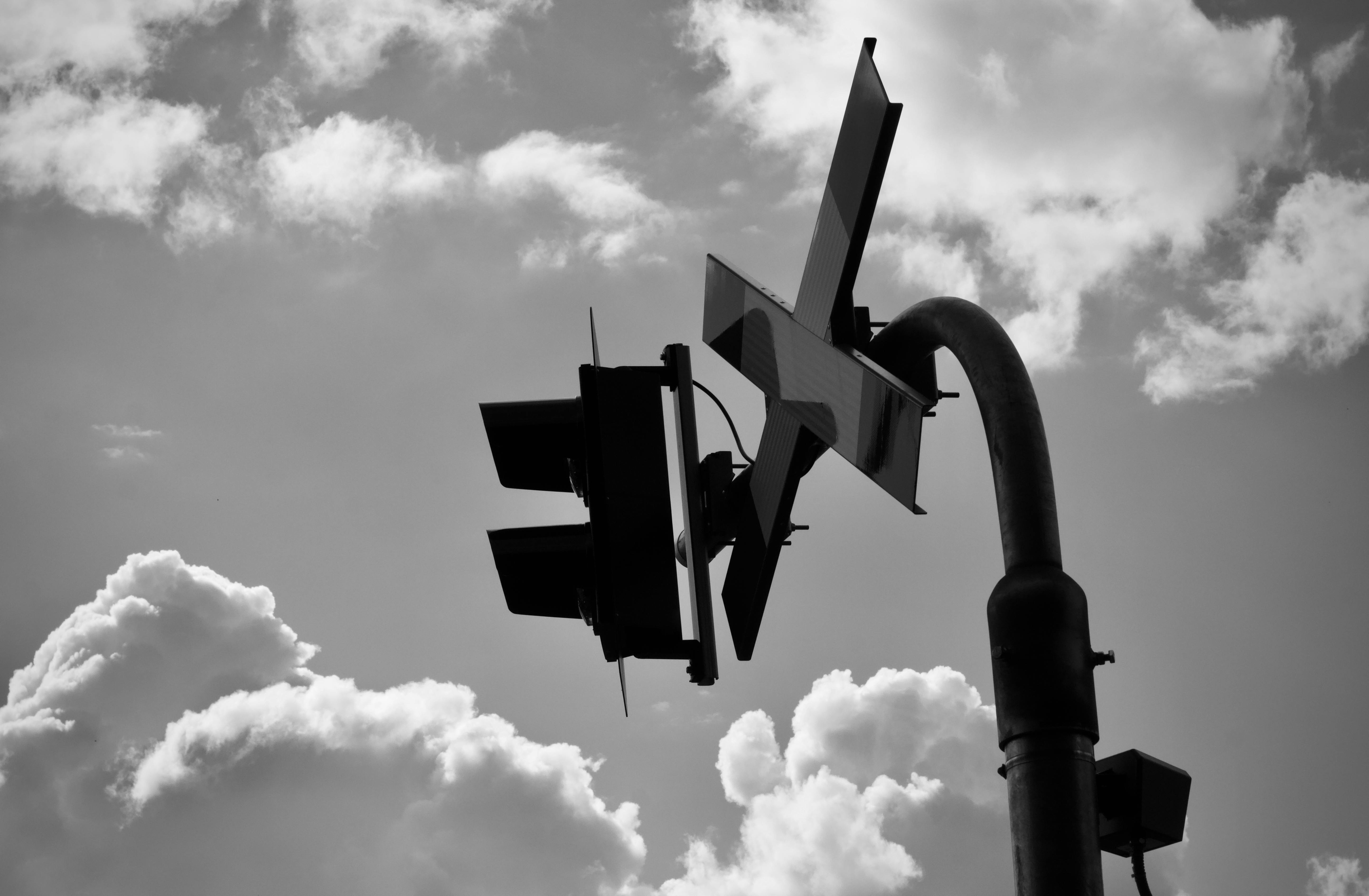 Free A striking silhouette of a traffic signal against a cloudy sky in black and white. Stock Photo