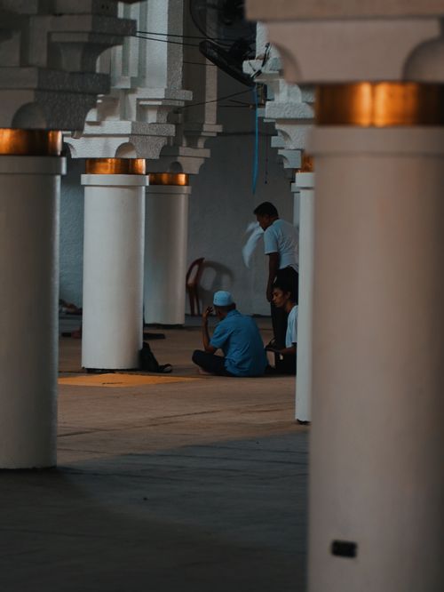 Free Men in a mosque engaged in prayer, surrounded by architectural columns and soft lighting. Stock Photo