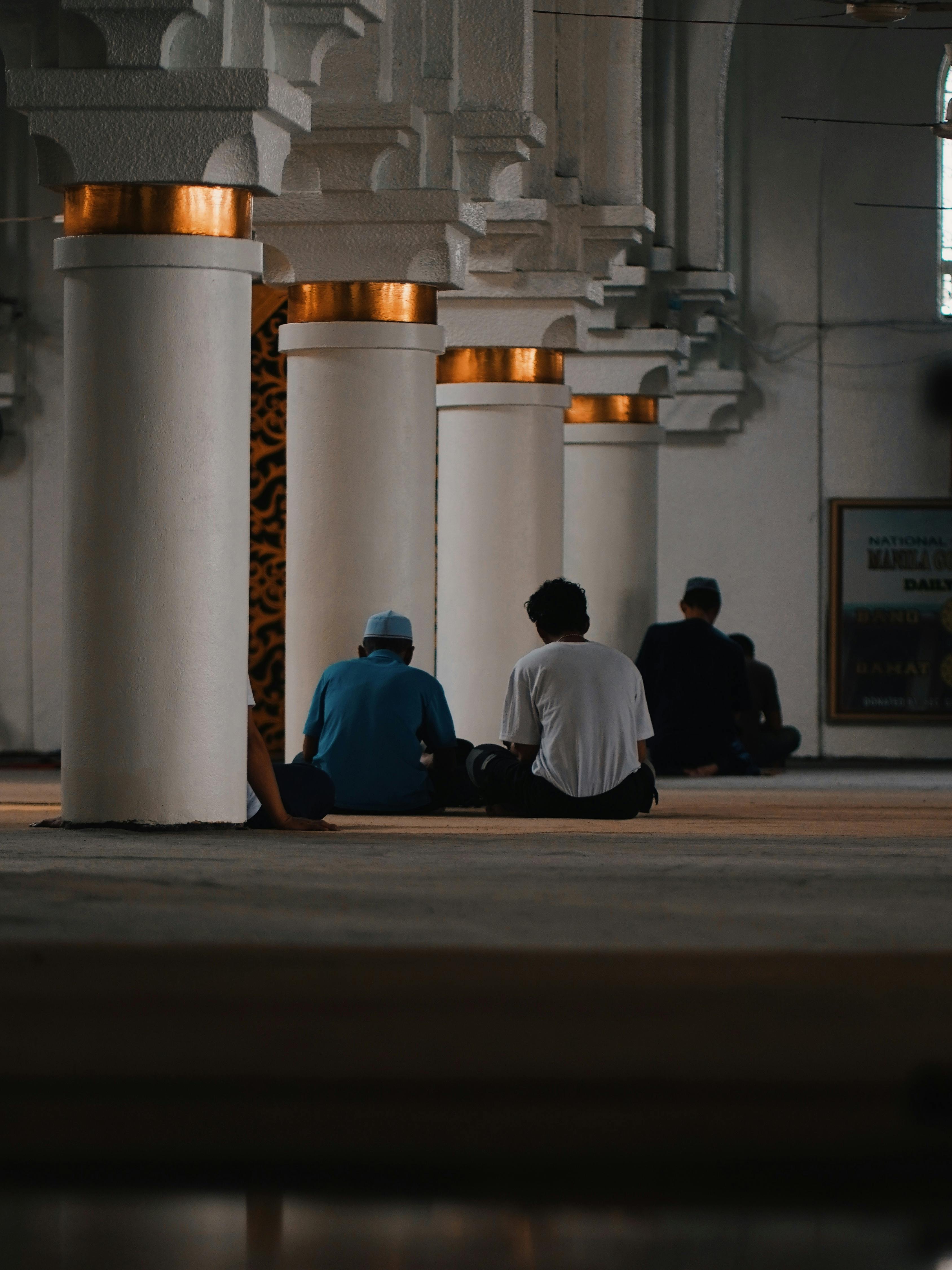 Miễn phí Cảnh bên trong một nhà thờ Hồi giáo với những người đang ngồi cầu nguyện giữa những cột trụ lớn. Ảnh lưu trữ