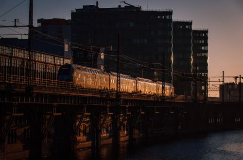 Free A train traverses a bridge silhouetted against a sunset in an urban setting. Stock Photo