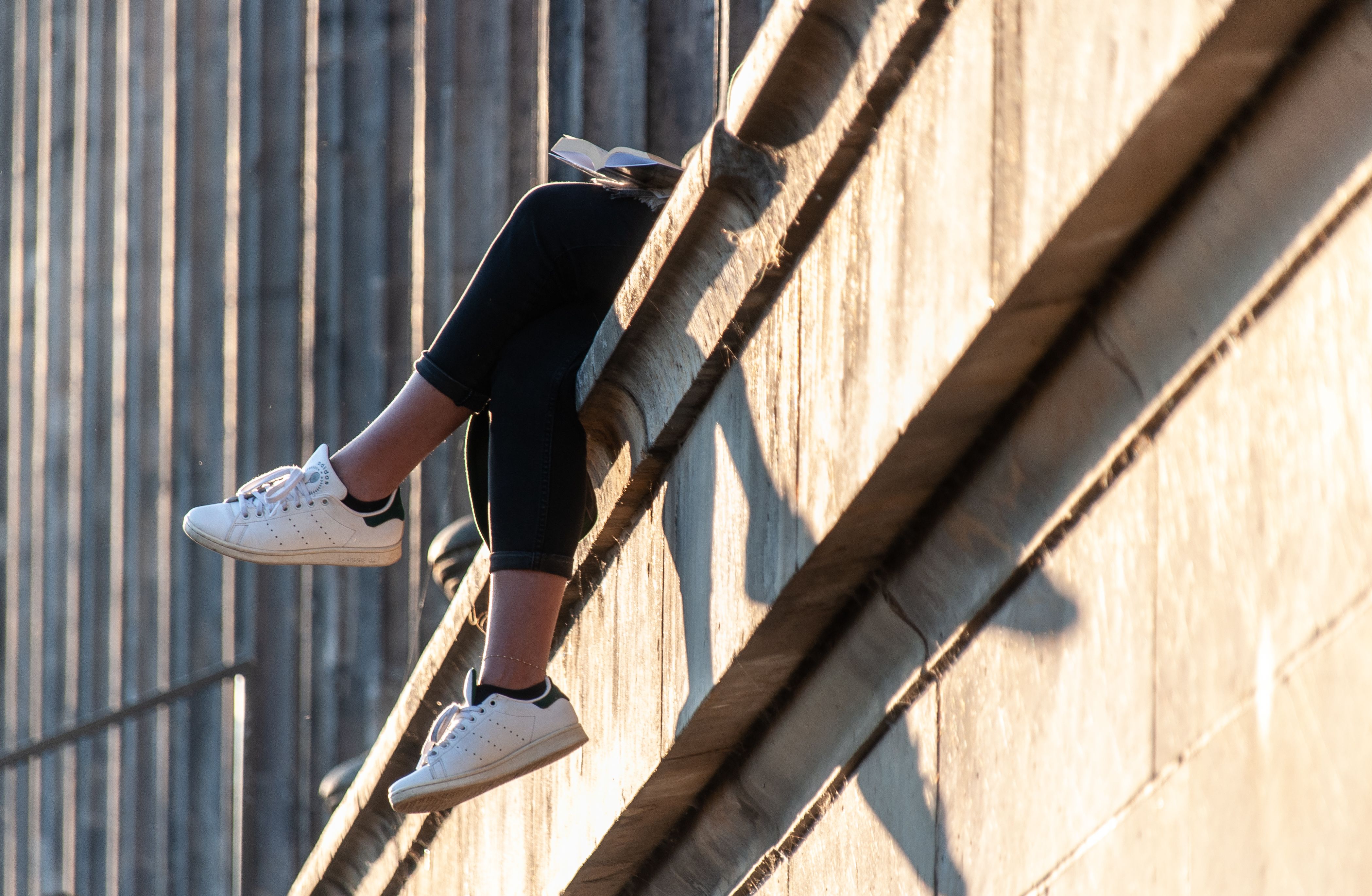 Person relaxing on building ledge at sunset · Free Stock Photo
