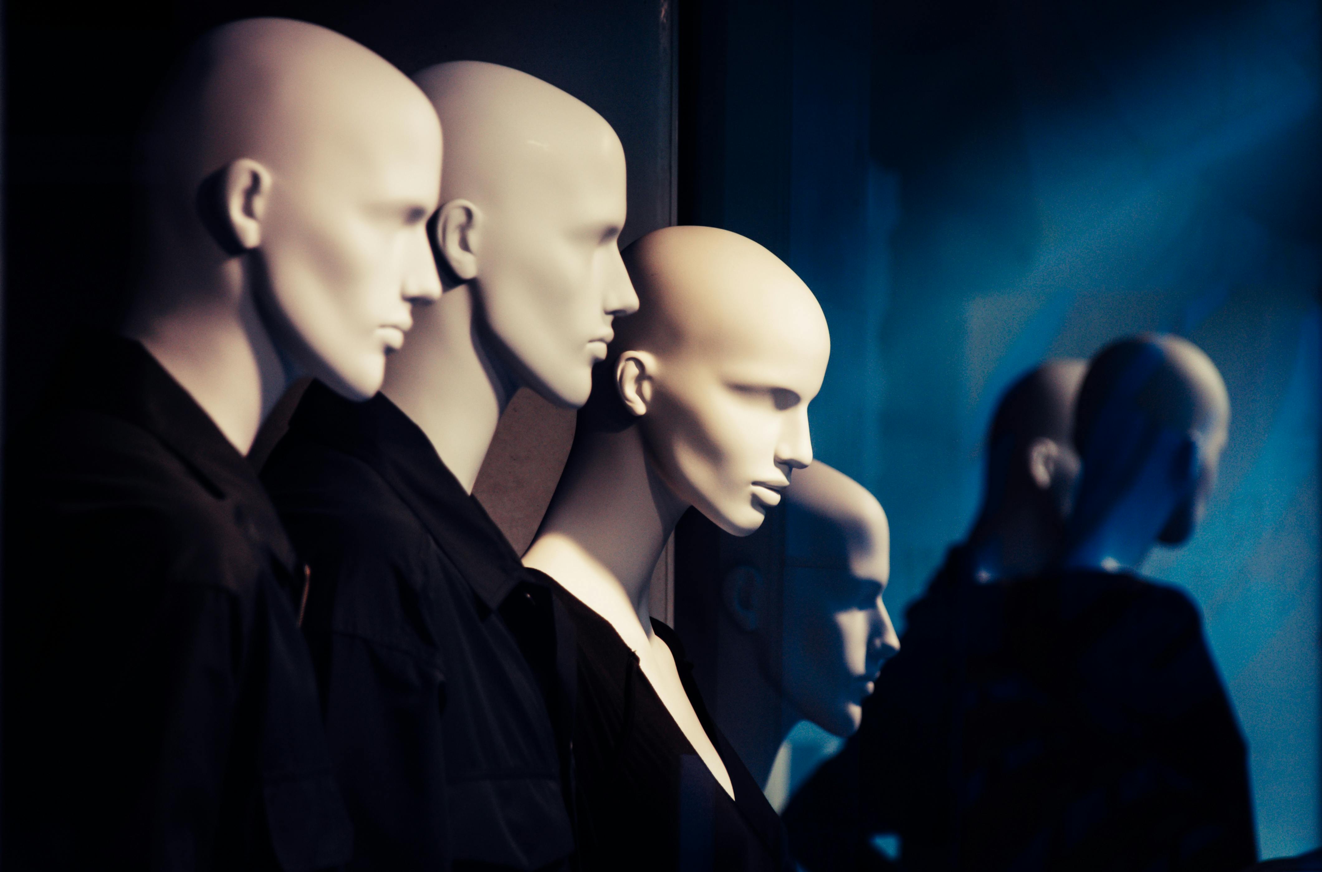 gratis Een rij mannequins in een etalage, met dramatische verlichting die een griezelige sfeer creëert. Stockfoto