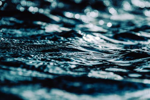 Free Artistic capture of rippling water surface reflecting sunlight, creating a dramatic and serene atmosphere. Stock Photo