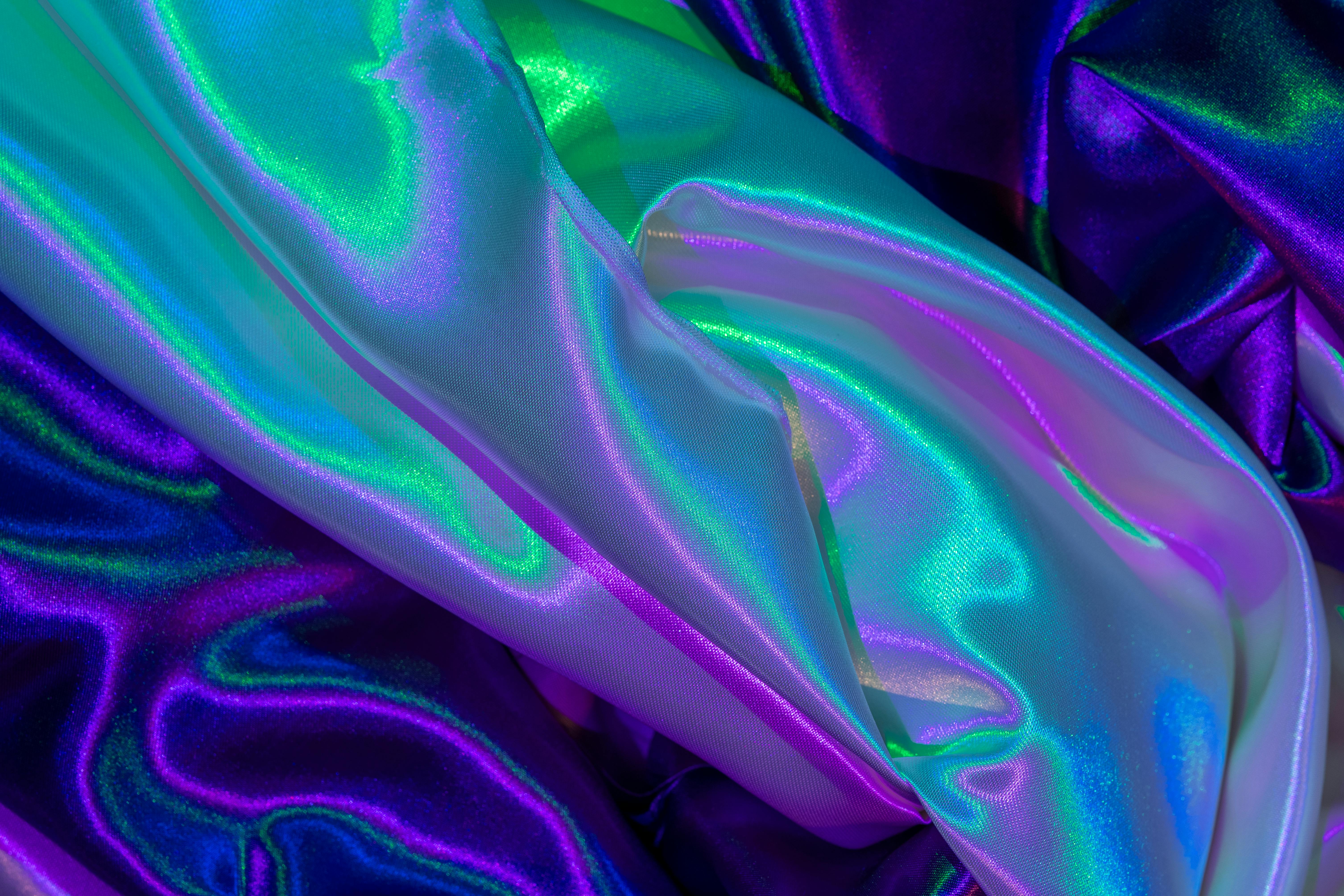 Free Close-up of colorful iridescent silk fabric with vibrant hues and glossy texture. Stock Photo