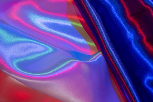 A close-up of satin fabric with colorful, abstract lighting creating a vibrant, glossy texture.