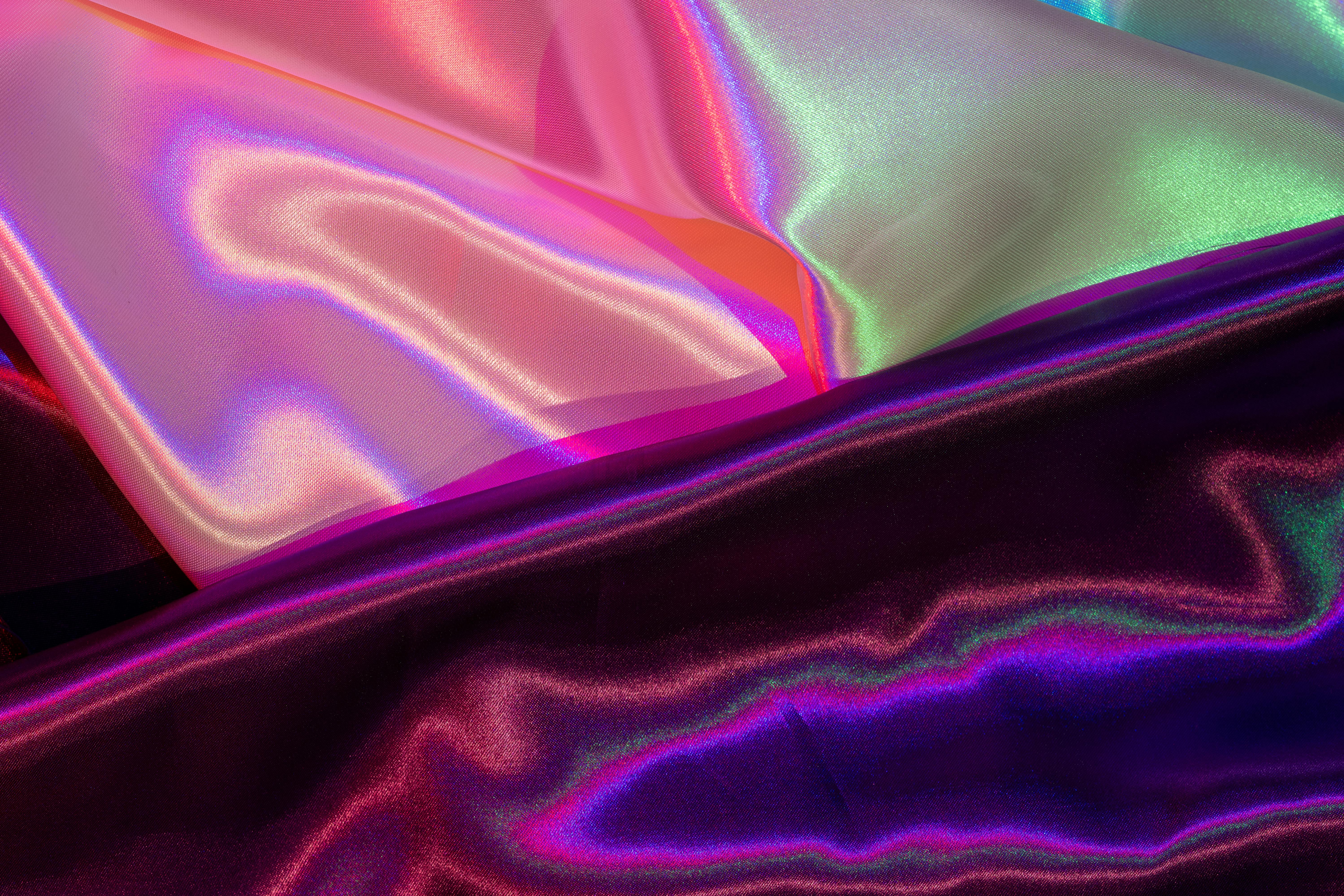 Gratuit O imagine captivantă a unui material satinat iridescent, care prezintă culori vibrante în gradient și o textură luxoasă. Fotografie de stoc