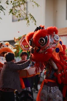 Chinese lion dance performers engage in a dynamic, colorful cultural celebration outdoors during the day.