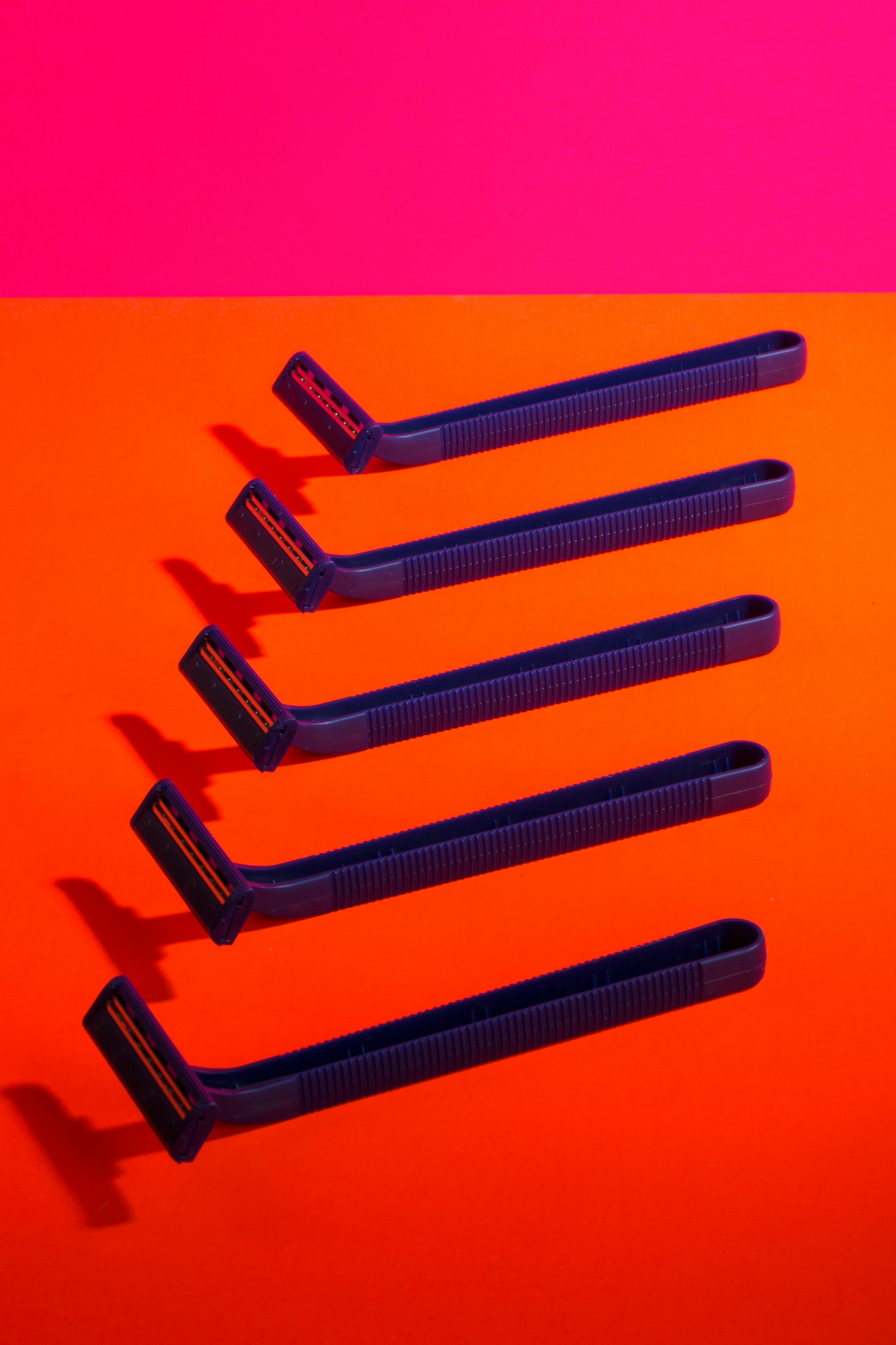 Zadarmo Modré žiletky usporiadané na žiarivo ružovom a oranžovom pozadí vytvárajú výrazný kontrast. Fotka z fotobanky