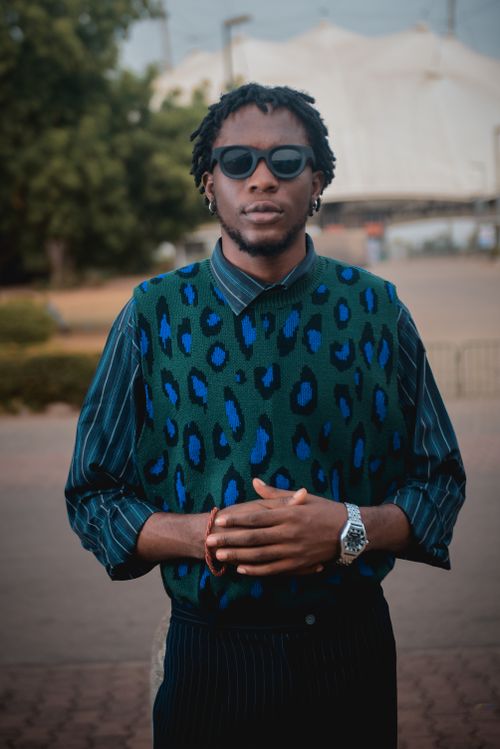 Free Fashionable young man with sunglasses wearing a patterned sweater, outdoors in an urban area. Stock Photo