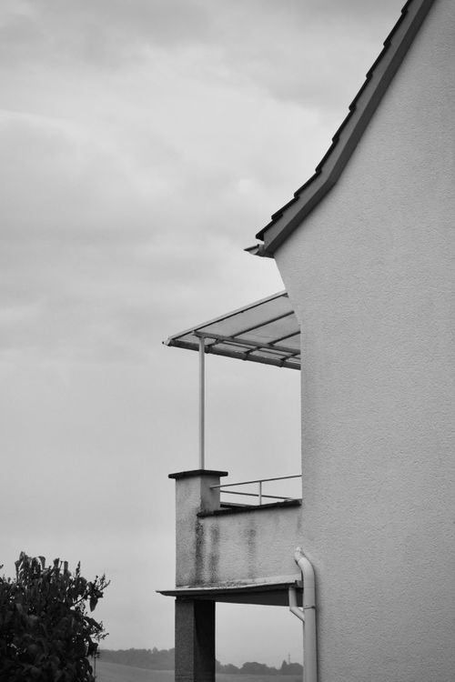 Free Black and white photo capturing minimalist architecture against cloudy sky. Stock Photo