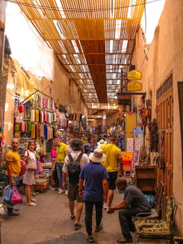Busy street scene in Marrakech medina featuring colorful shops and local visitors. Experience Moroccan culture.