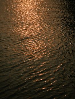 Golden sunset reflecting on rippling water creating a serene and peaceful ambiance.