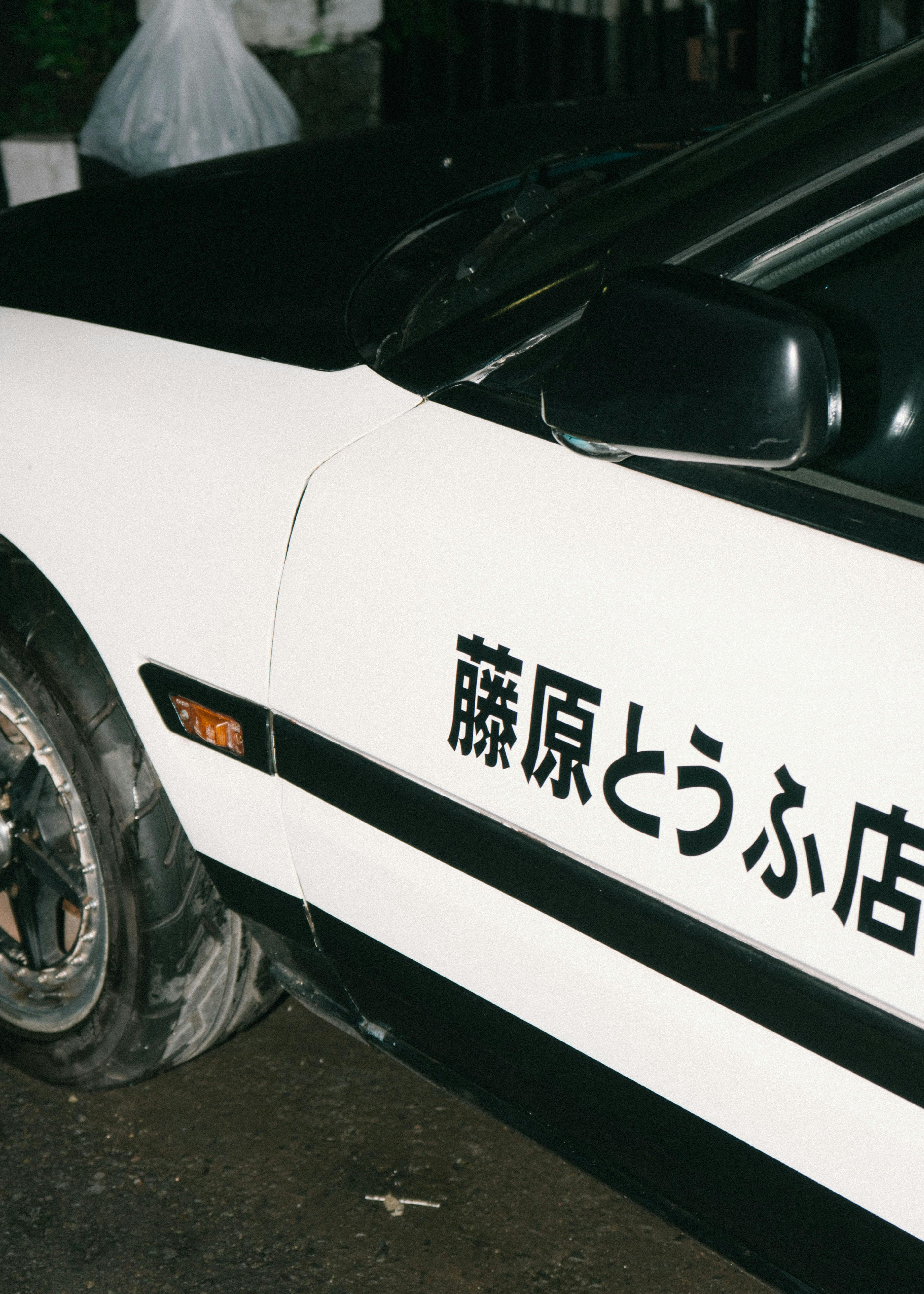 Bezpłatne Zbliżenie japońskiego samochodu z napisem kanji na boku, zrobione nocą. Zdjęcie z galerii