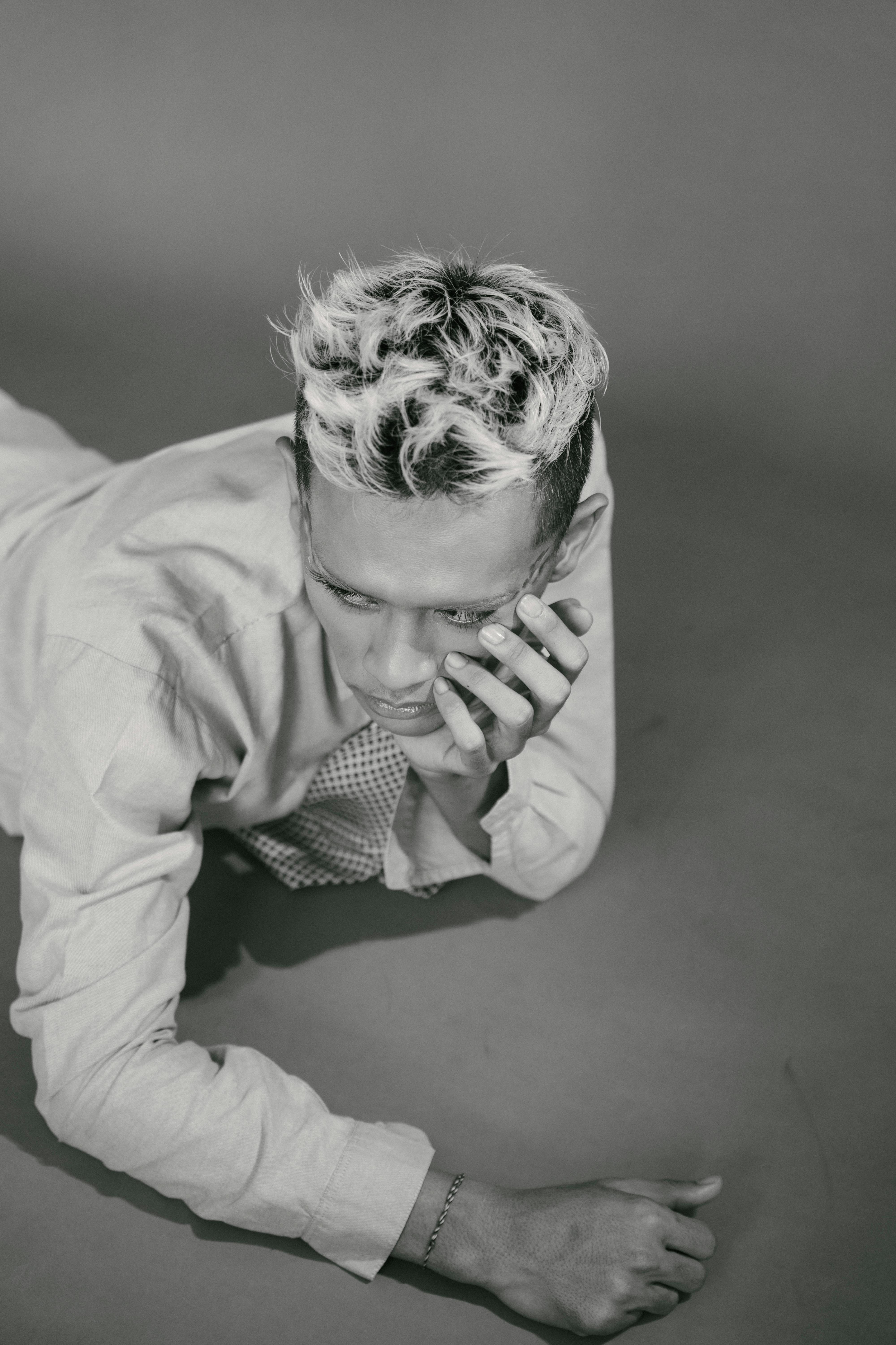 bezplatná Monochromatický portrét osoby se stylovými vlasy zamyšleně ležící na rovném povrchu. Základová fotografie