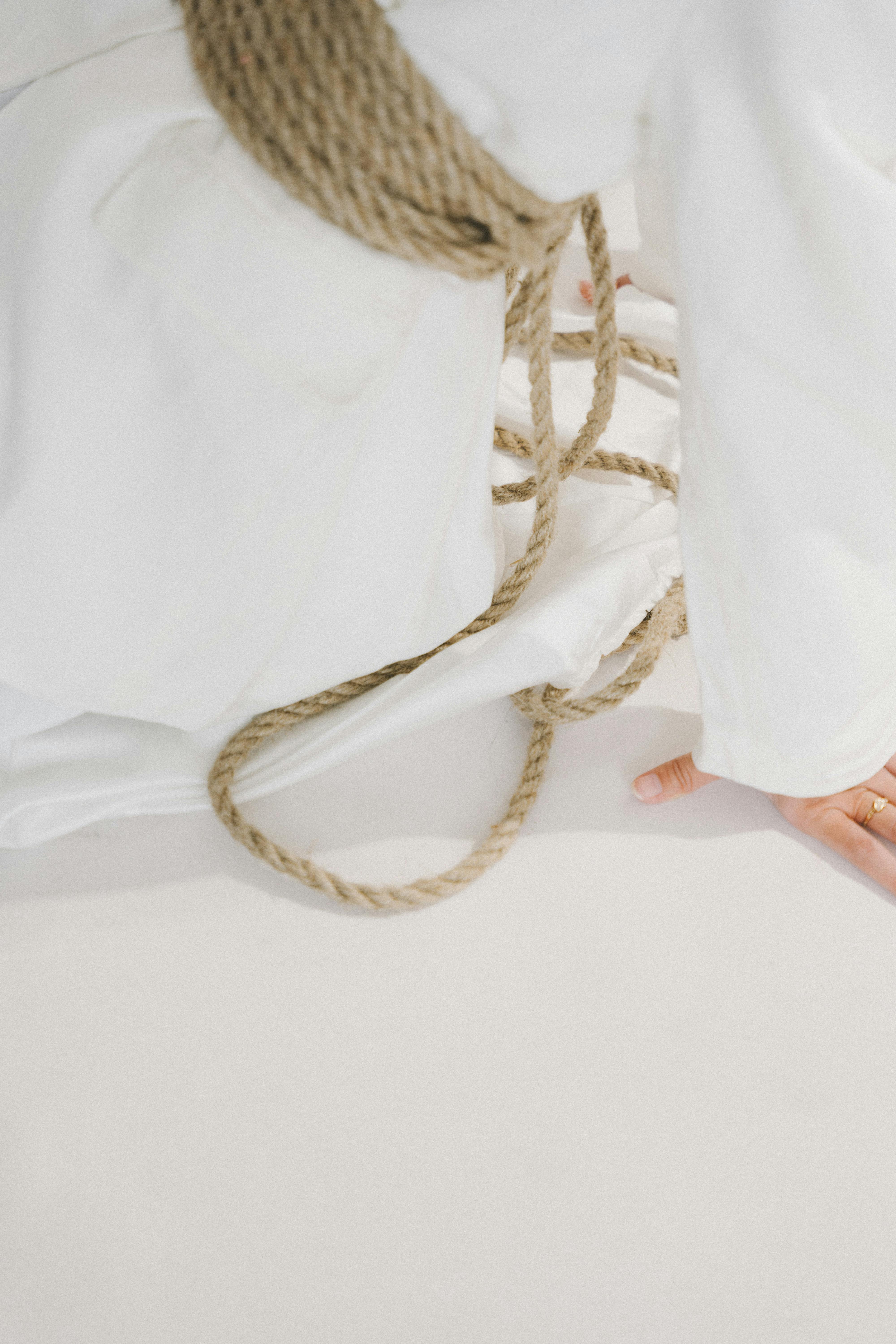 Free Minimalist composition featuring rope entwined on a white fabric backdrop. Stock Photo