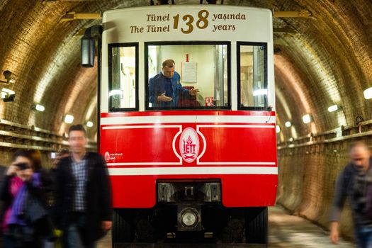 A historic red subway train in Istanbul's tunnel system, featuring commuters and unique design.