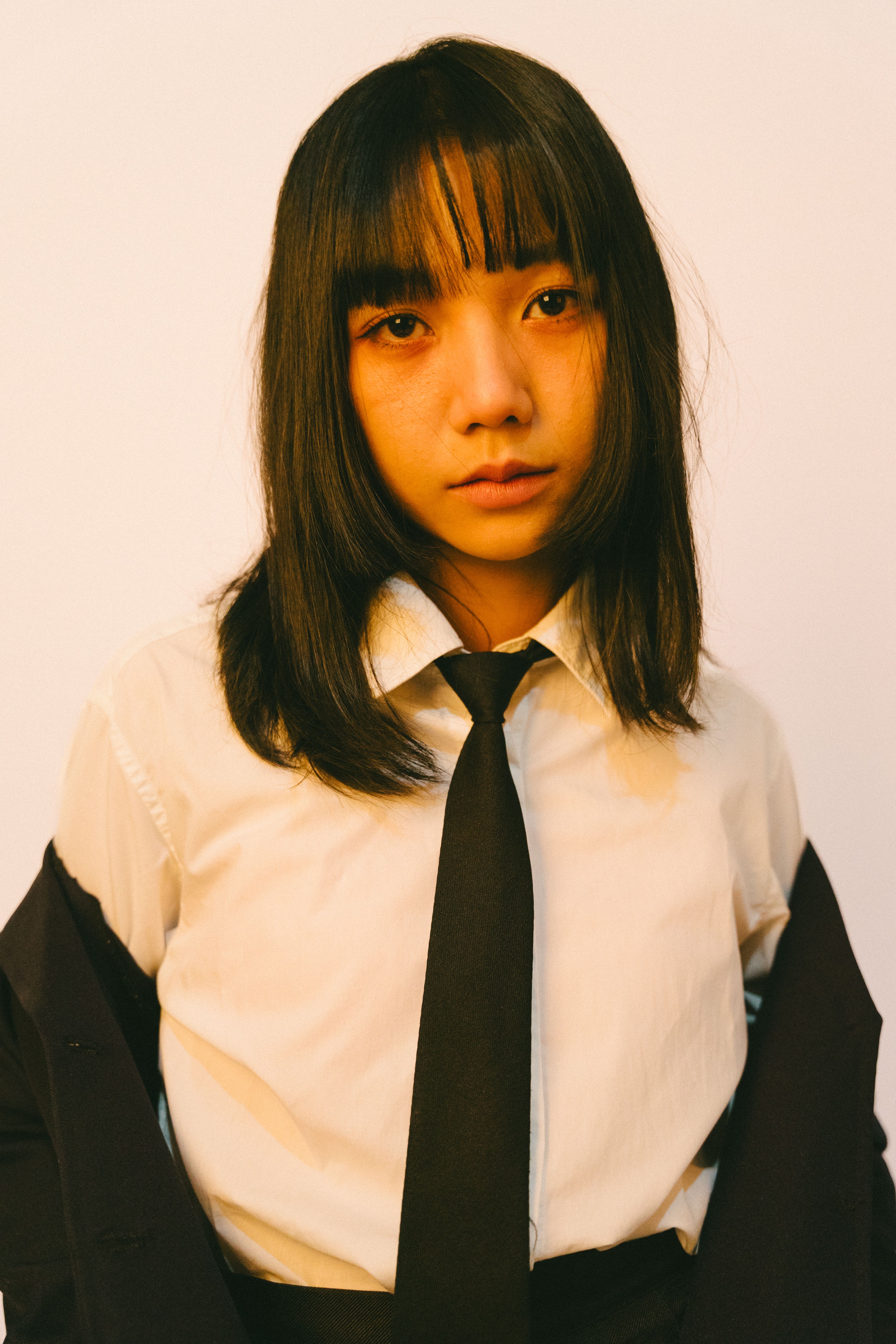 A young adult in formal attire, looking directly at the camera with a neutral expression.