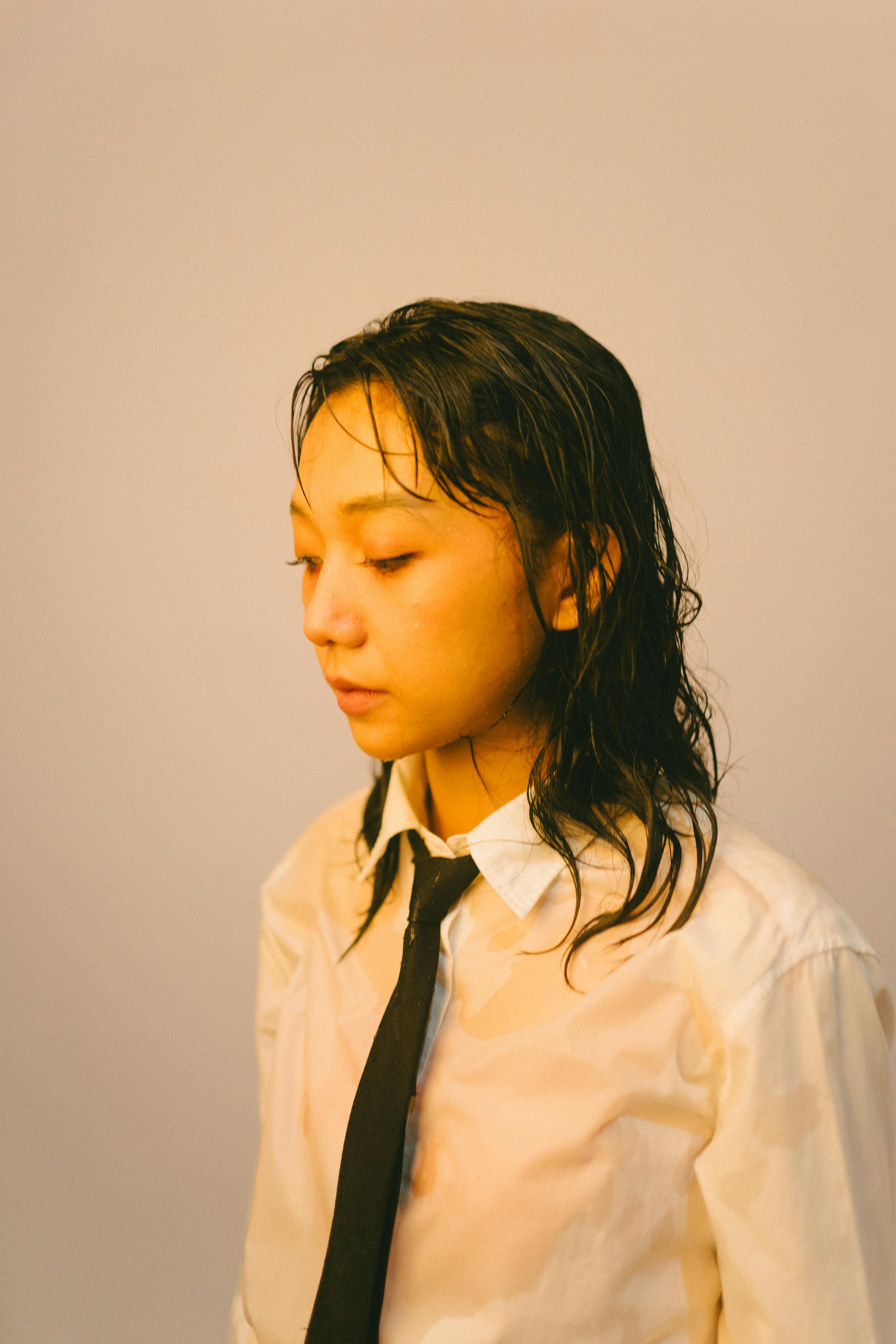 Ücretsiz Islak saçlı, resmi gömlek ve kravat giymiş Asyalı bir kadının sakin, içe dönük portresi. Stok Fotoğraflar