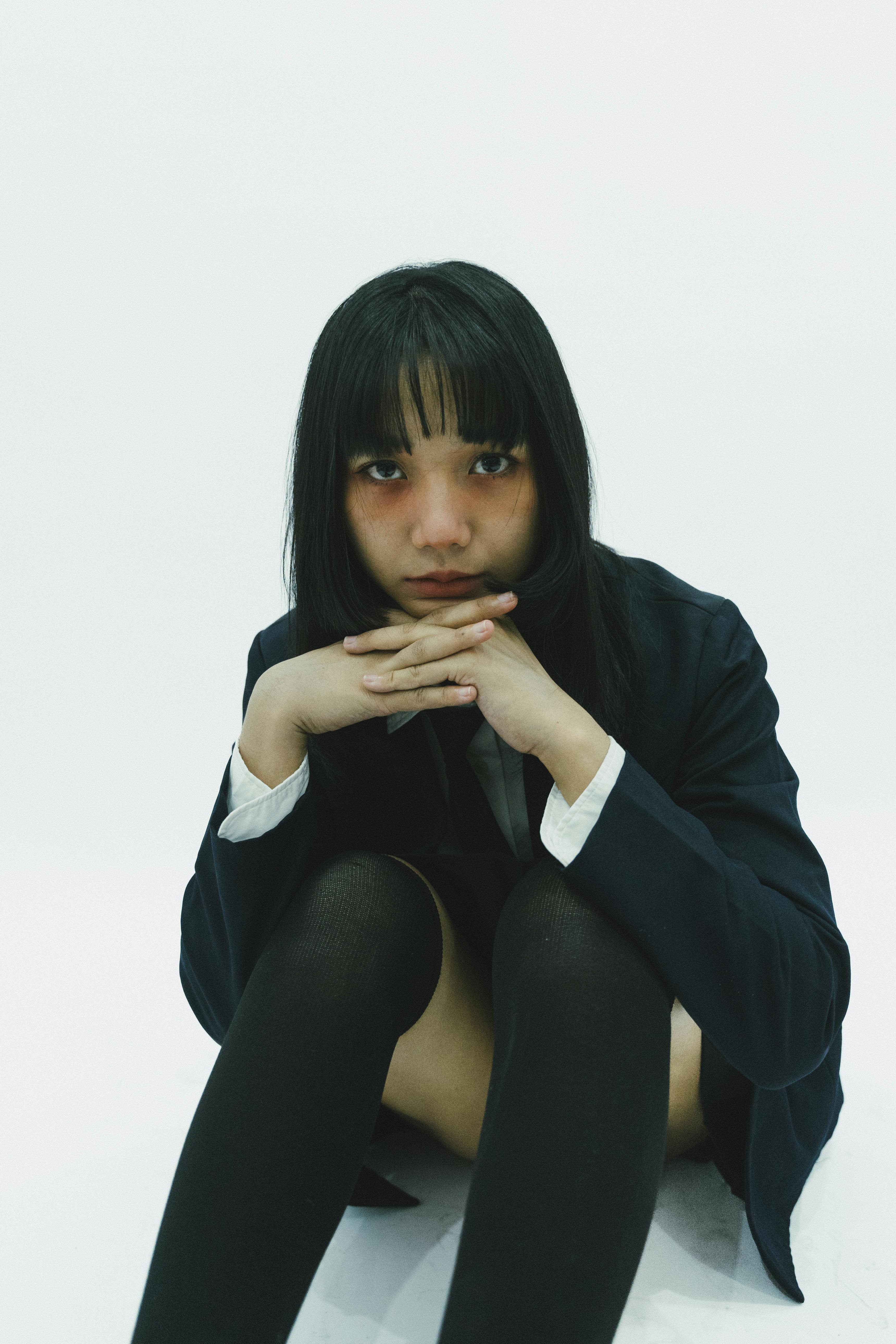 Miễn phí Một phụ nữ trẻ trầm tư trong chiếc áo blazer tạo dáng đầy suy nghĩ trước phông nền trắng tối giản. Ảnh lưu trữ