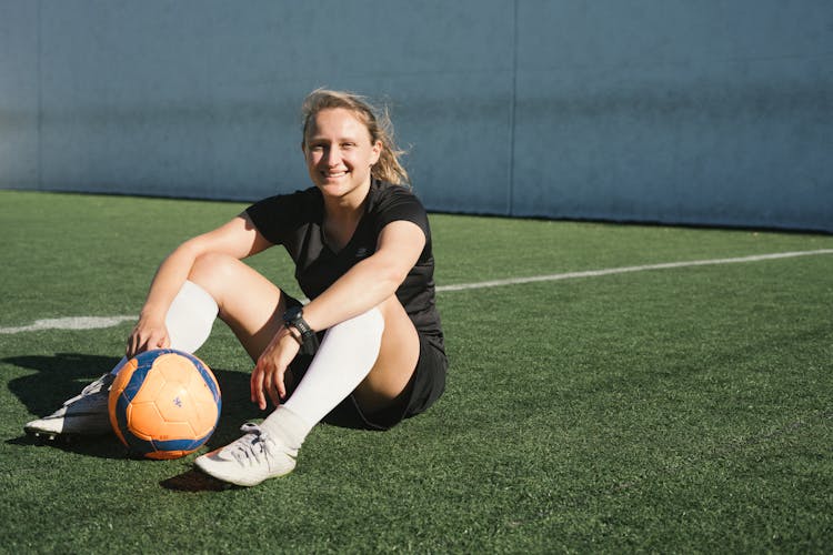 Soccer Player Sitting On A Green Field