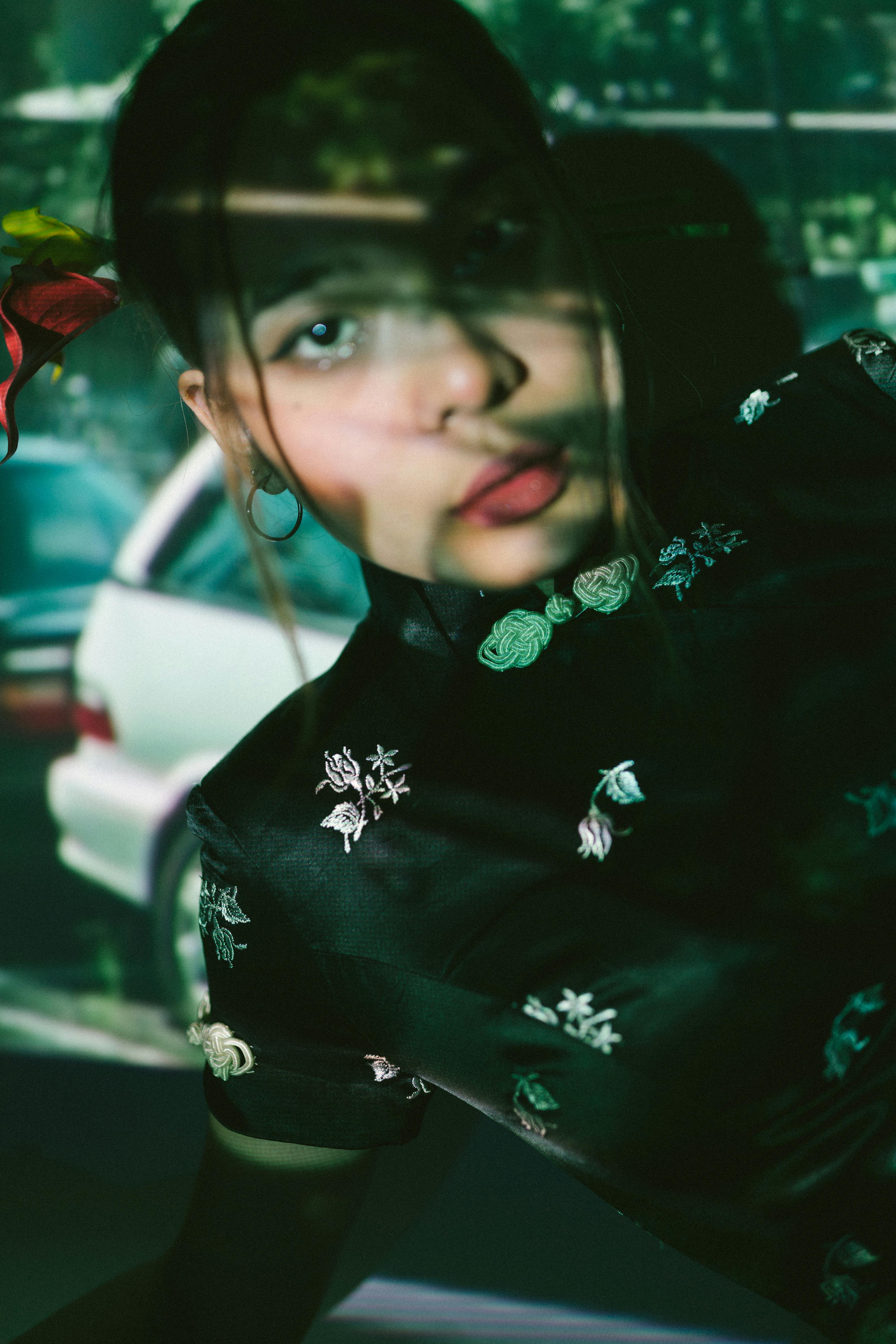 Free Creative portrait of a woman with floral dress and shadow play in urban setting. Stock Photo