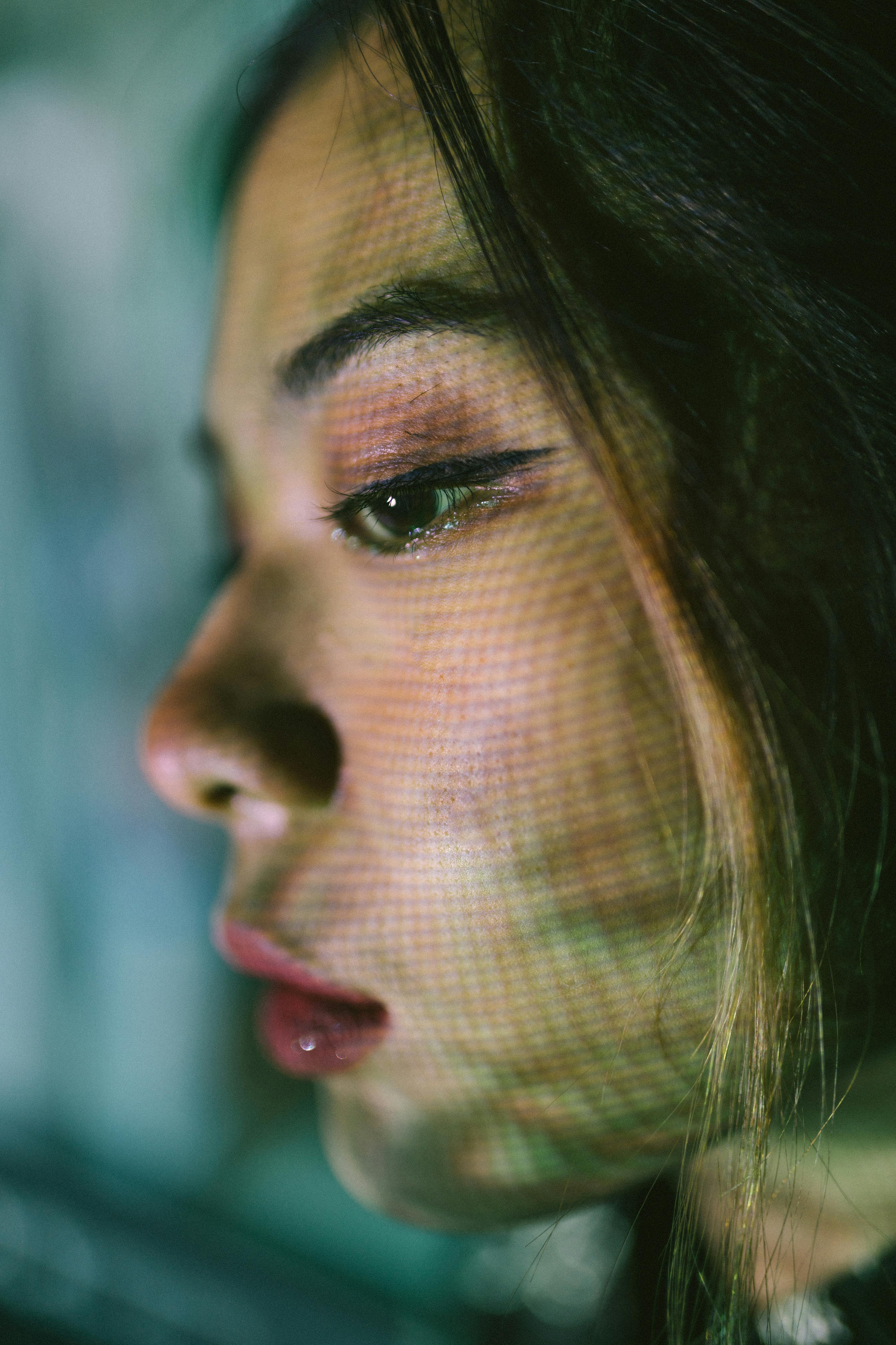 Bezpłatne Zbliżenie, artystyczny portret kobiety z kolorowymi wzorami świetlnymi na twarzy. Zdjęcie z galerii