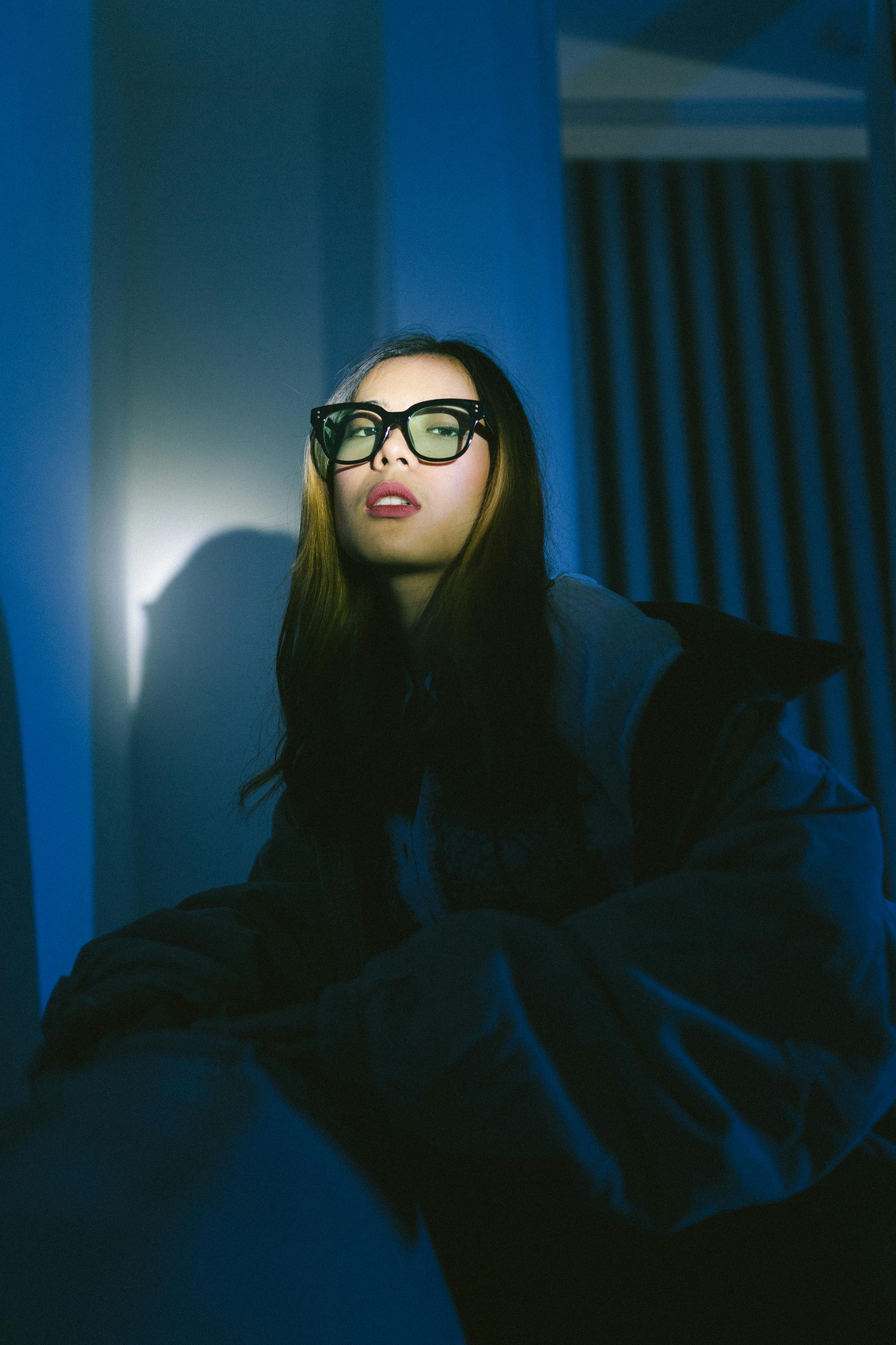 Gratis Retrato artístico de una mujer con gafas con una iluminación dramática que crea una atmósfera melancólica. Foto de stock