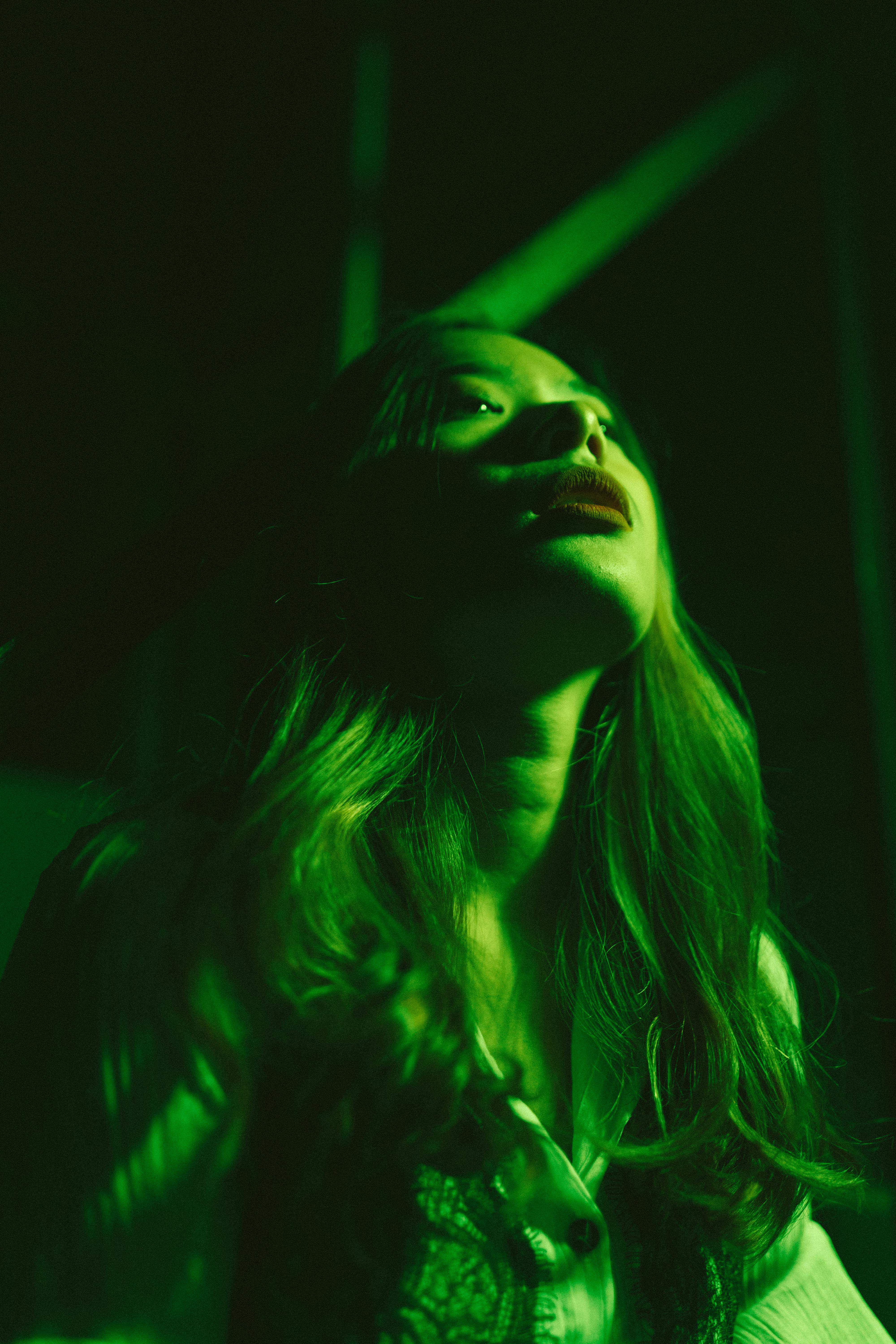 Gratuit Portret sumbru al unei femei cu o iluminare verde dramatică, evocând mister. Fotografie de stoc