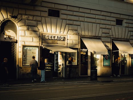 Street view of a gelato shop in Rome during evening with people enjoying the urban ambiance.