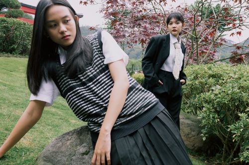 Free Two stylish young women pose in a serene garden, showcasing fashion and nature. Stock Photo
