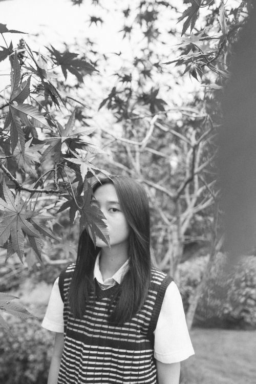 Free Black and white portrait of a young woman among trees, expressive and serene. Stock Photo