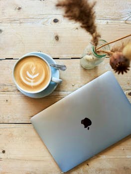 Inviting cafe scene with a latte and laptop on a wooden table, perfect for remote work.