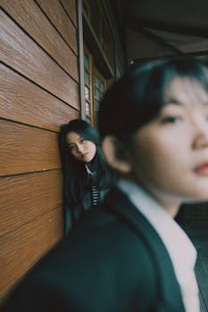 Moody portrait of two women, one in focus and one blurred, against a wooden backdrop.