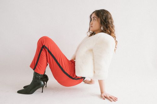 Free Fashionable woman in red pants and a white jacket posing indoors. Stock Photo