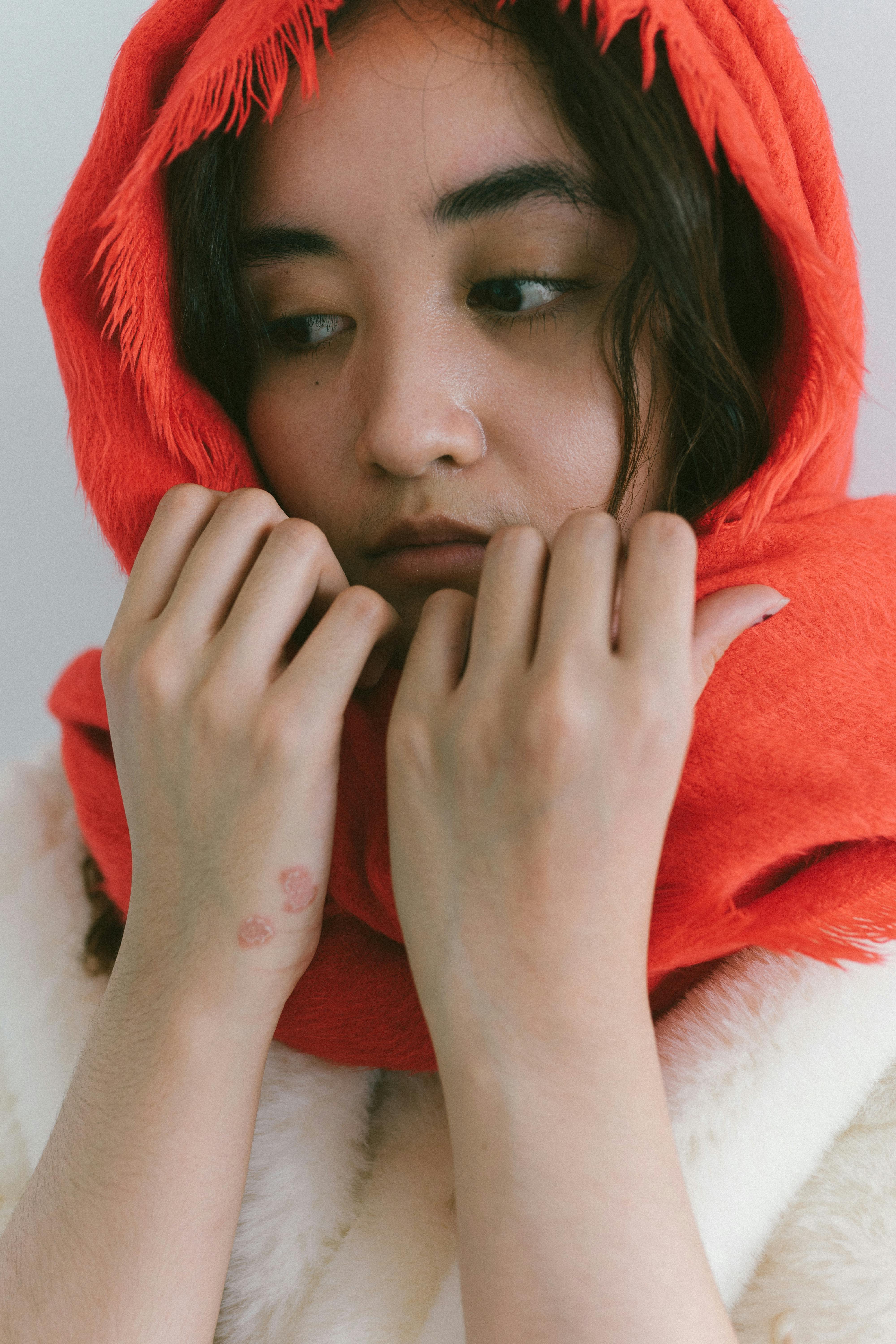 Miễn phí Một người phụ nữ với chiếc khăn quàng đỏ và vẻ mặt trầm tư, tạo nên một bầu không khí ấm áp và suy ngẫm. Ảnh lưu trữ