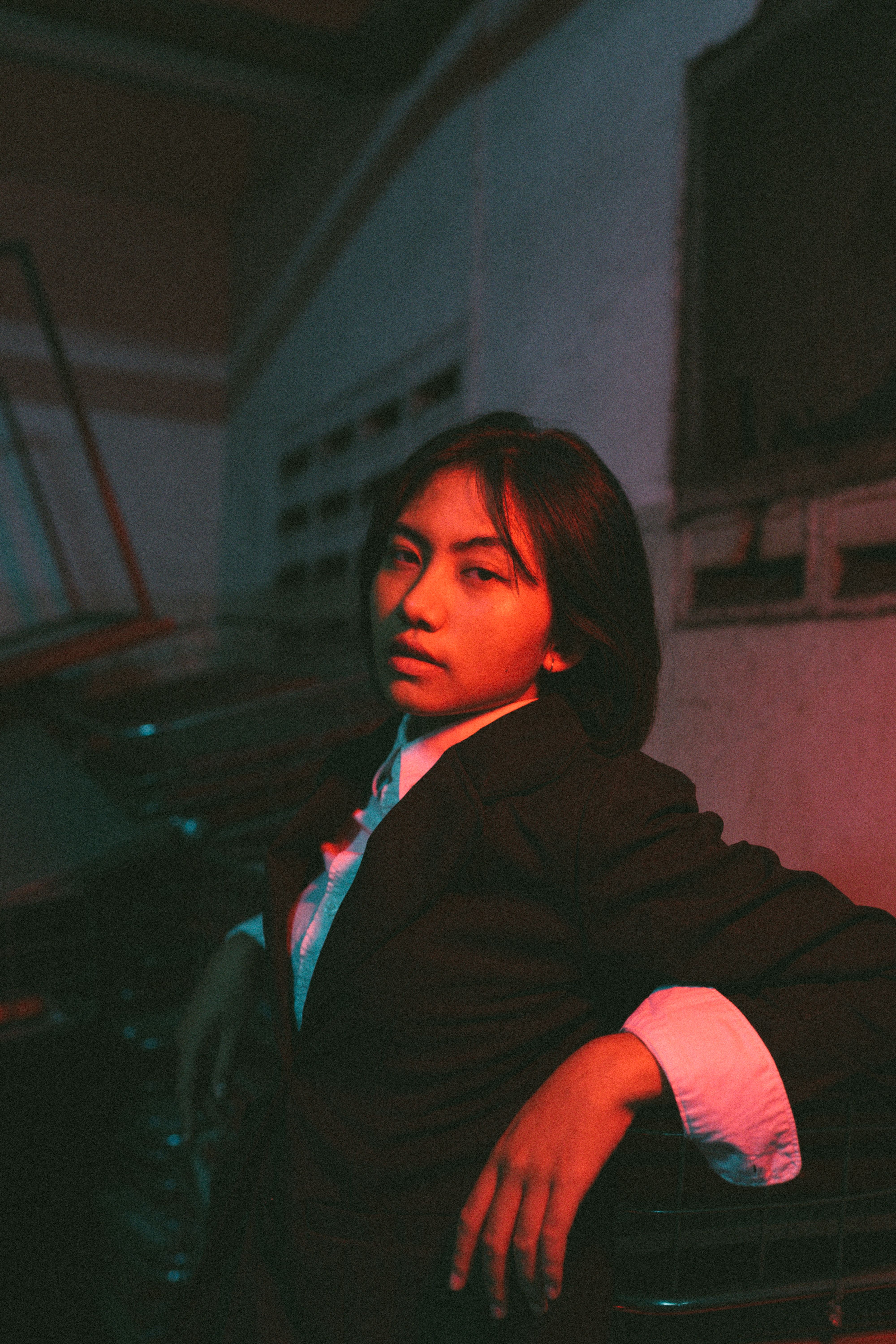 Captivating moody portrait of a woman in a suit with dramatic lighting in an industrial setting.