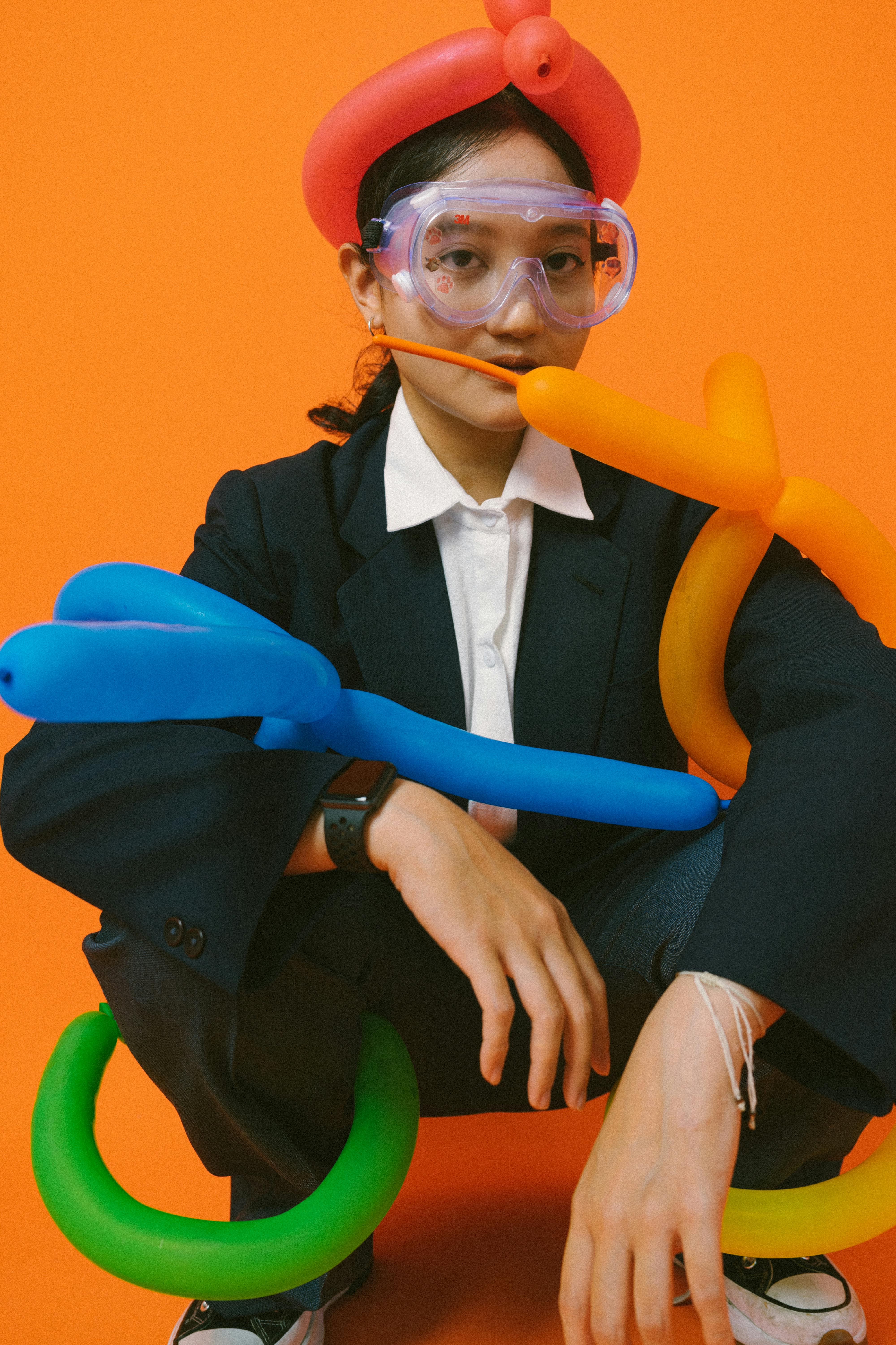 Ücretsiz Canlı turuncu bir arka plan önünde, balon ve gözlük takmış bir kişinin renkli portresi. Stok Fotoğraflar