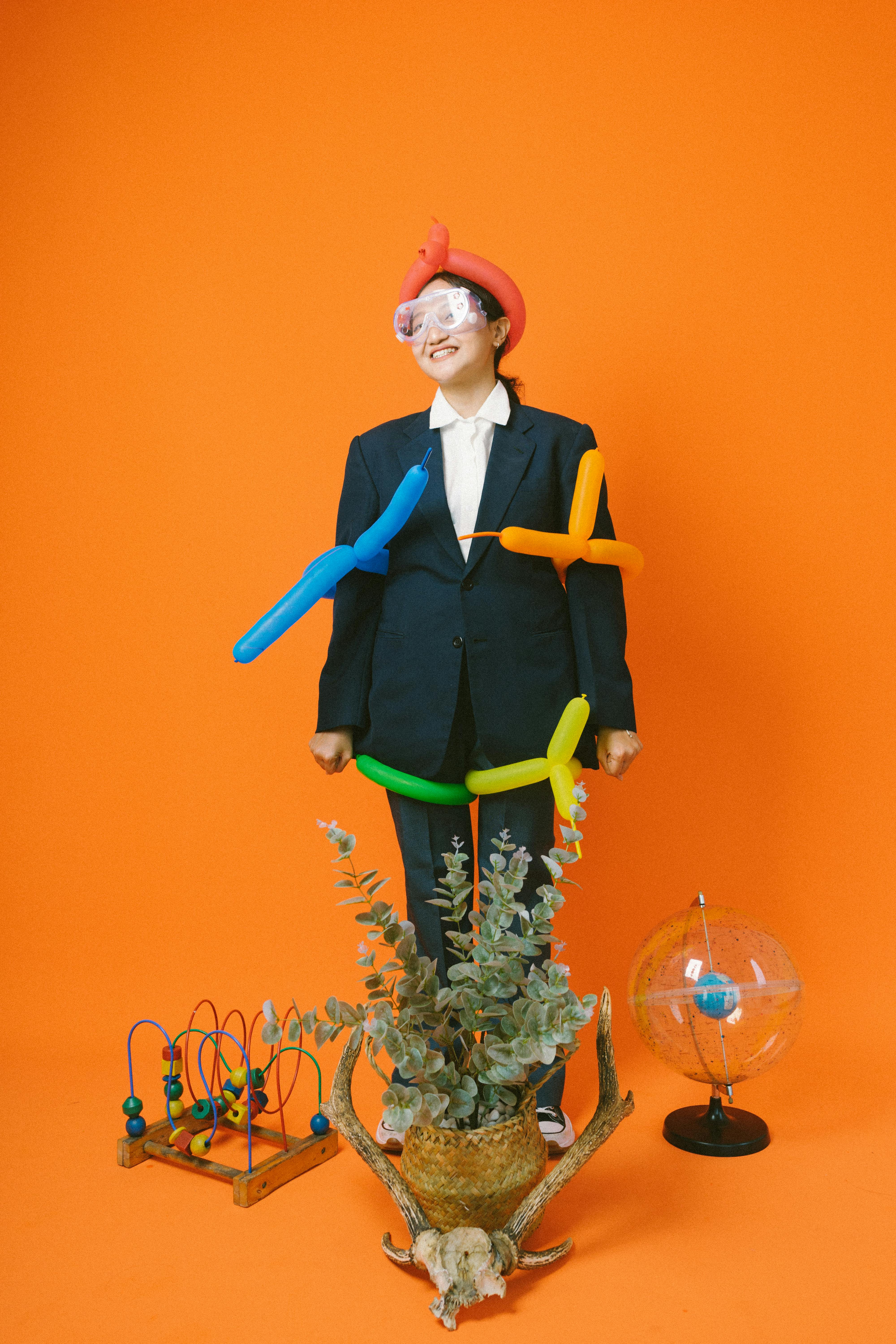 Ücretsiz Turuncu bir arka plan önünde, yaratıcılığı simgeleyen, neşeli bir balon kostümü giymiş bir kişi. Stok Fotoğraflar