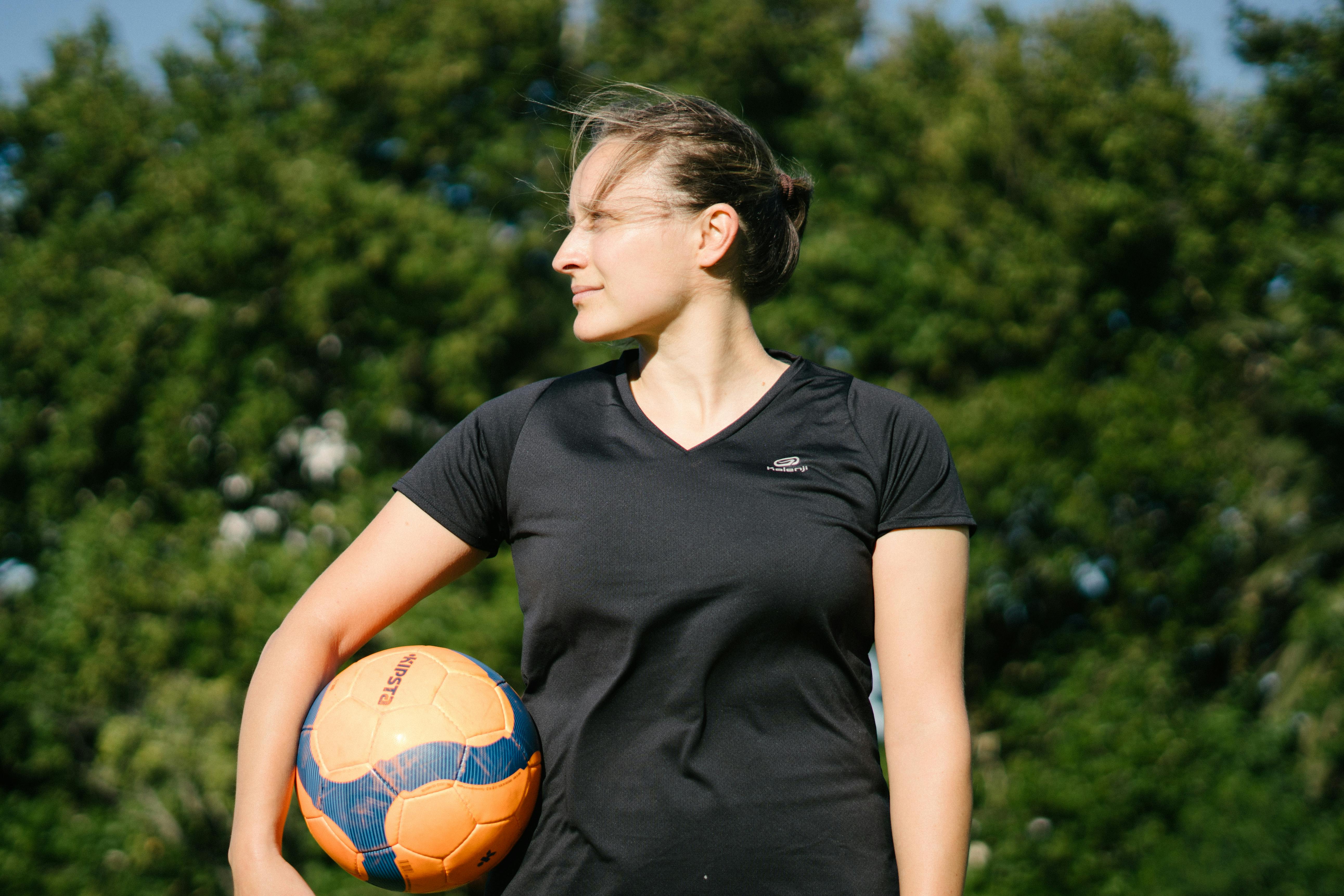 Mulher De Camiseta Preta Com Gola Redonda Segurando Uma Bola De Futebol · Foto profissional gratuita