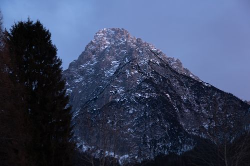 Free Majestic snow-capped mountain with dark trees captured during twilight creates a dramatic scene. Stock Photo