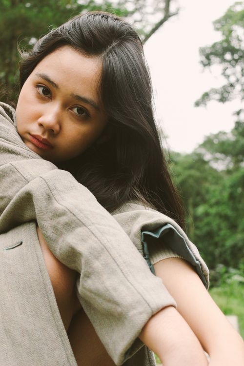 Free A young woman poses thoughtfully in a natural outdoor setting, conveying a sense of introspection and calm. Stock Photo