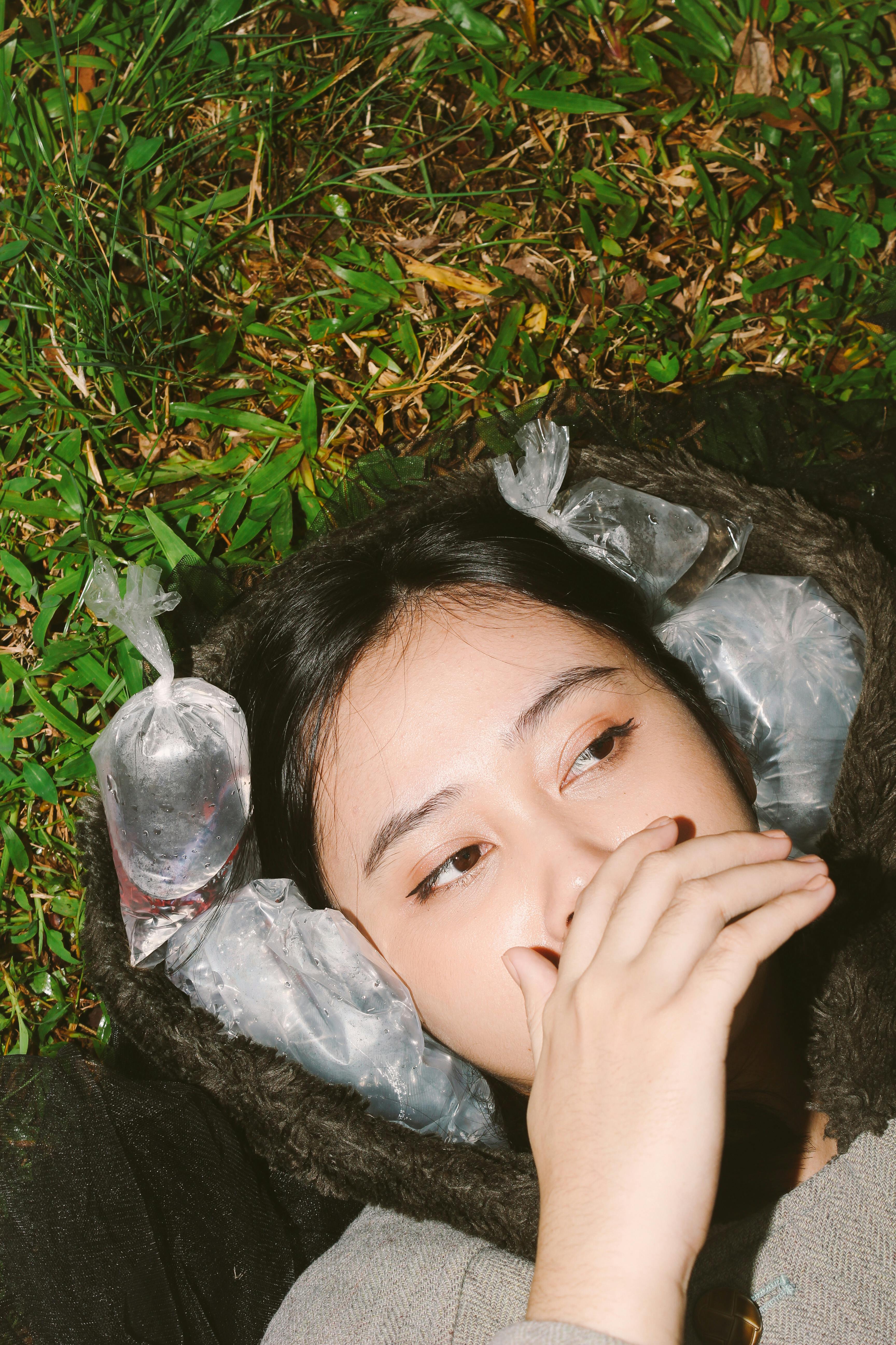 Ücretsiz Bir kadın buz paketleriyle çevrili çimenlerin üzerinde uzanarak, doğanın huzurlu bir anını yakalıyor. Stok Fotoğraflar