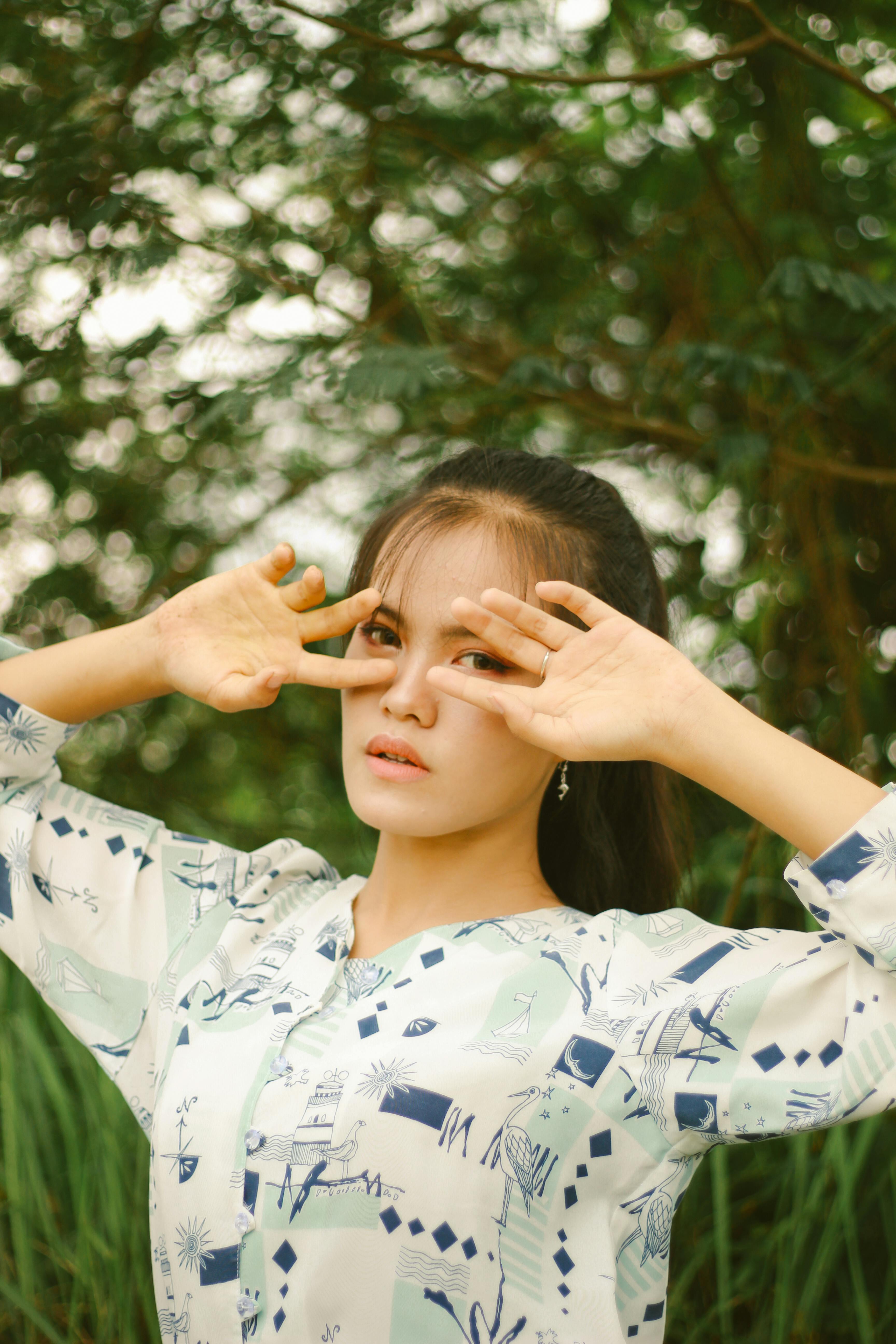 免费 一位女子双手托腮，在郁郁葱葱的绿植映衬下摆出姿势。 素材图片