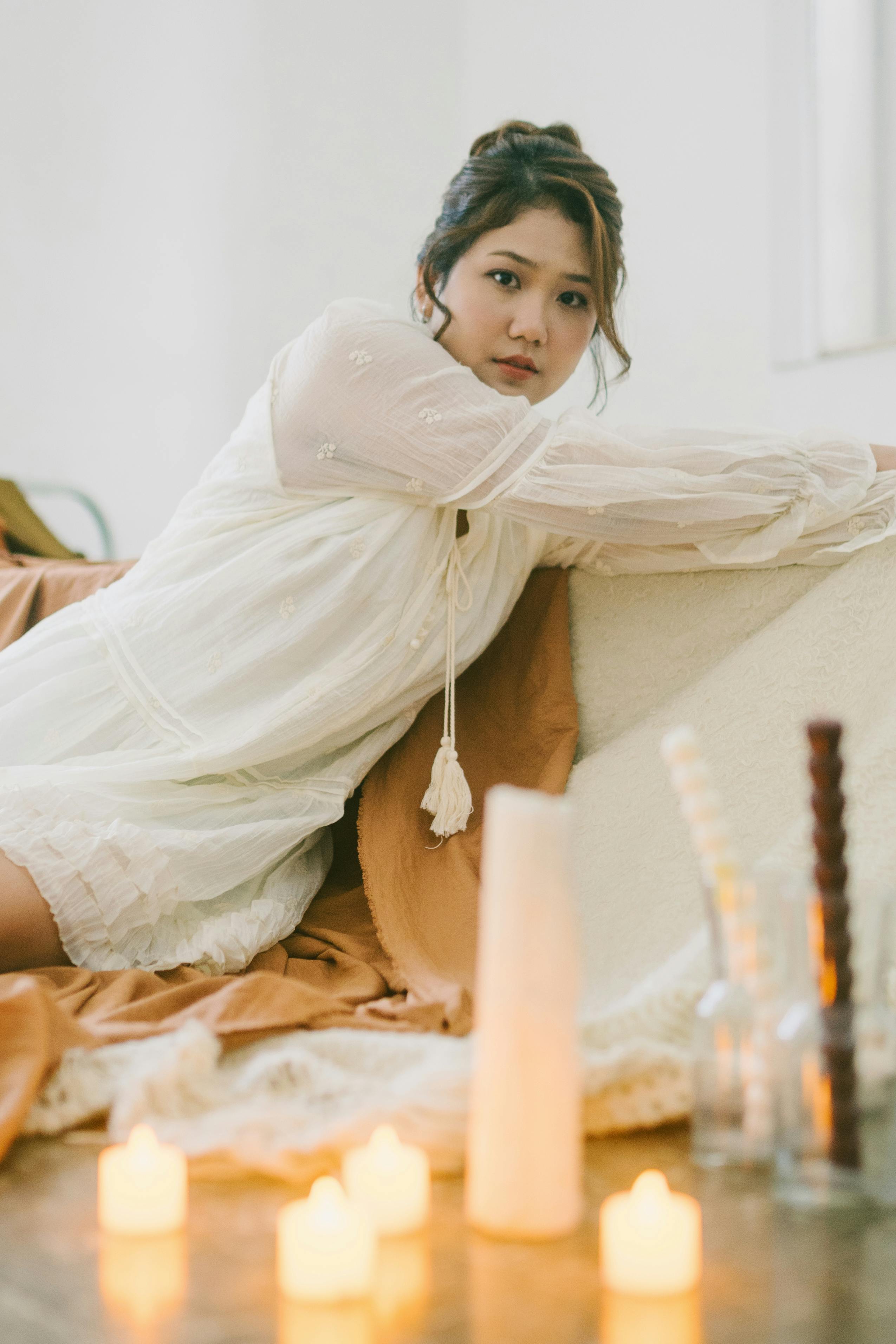 Serene woman surrounded by candles in elegant peaceful pose, capturing intimate relaxation and soft glow